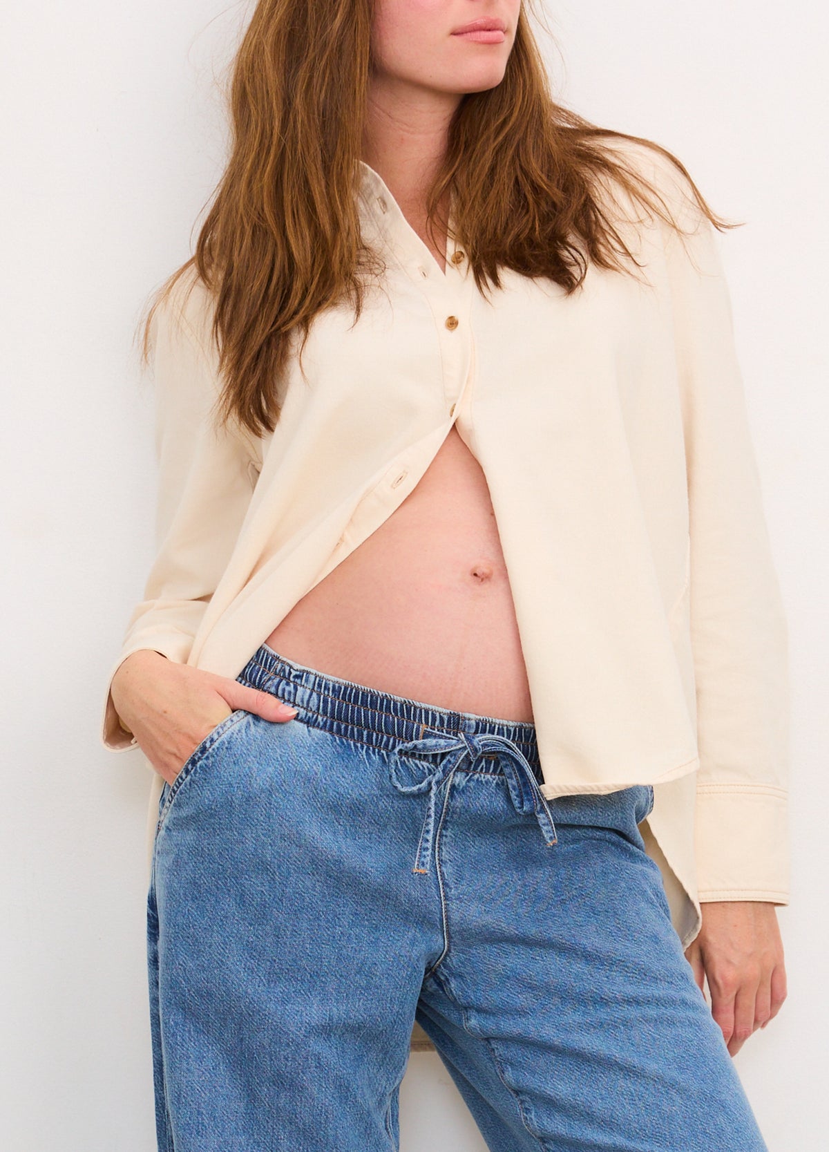 Cream-colored drapey maternity denim shirt paired with loose blue drawstring boyfriend jeans.