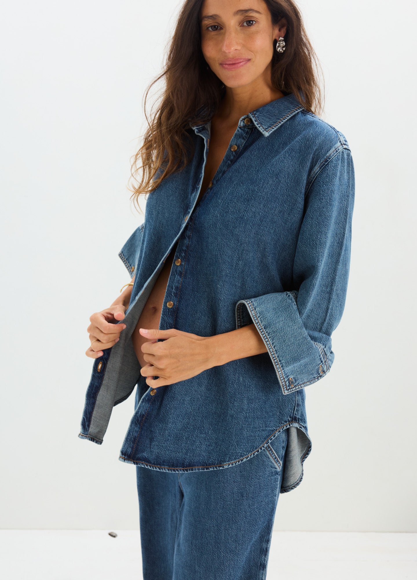 Loose-fit medium blue denim shirt with rolled sleeves, designed for maternity comfort.