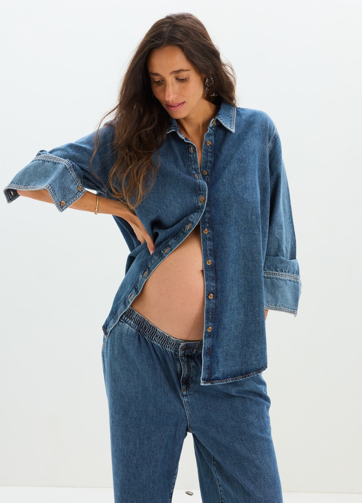 Dark blue denim boyfriend shirt with long sleeves, unbuttoned to reveal maternity belly, paired with matching denim pants.