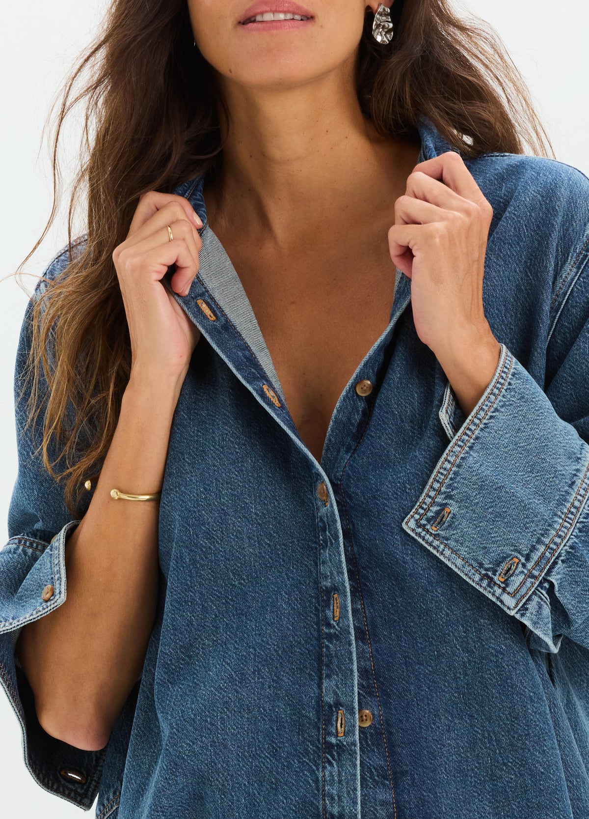 Loose-fit medium blue denim shirt with dropped shoulders and button front, designed for maternity wear.