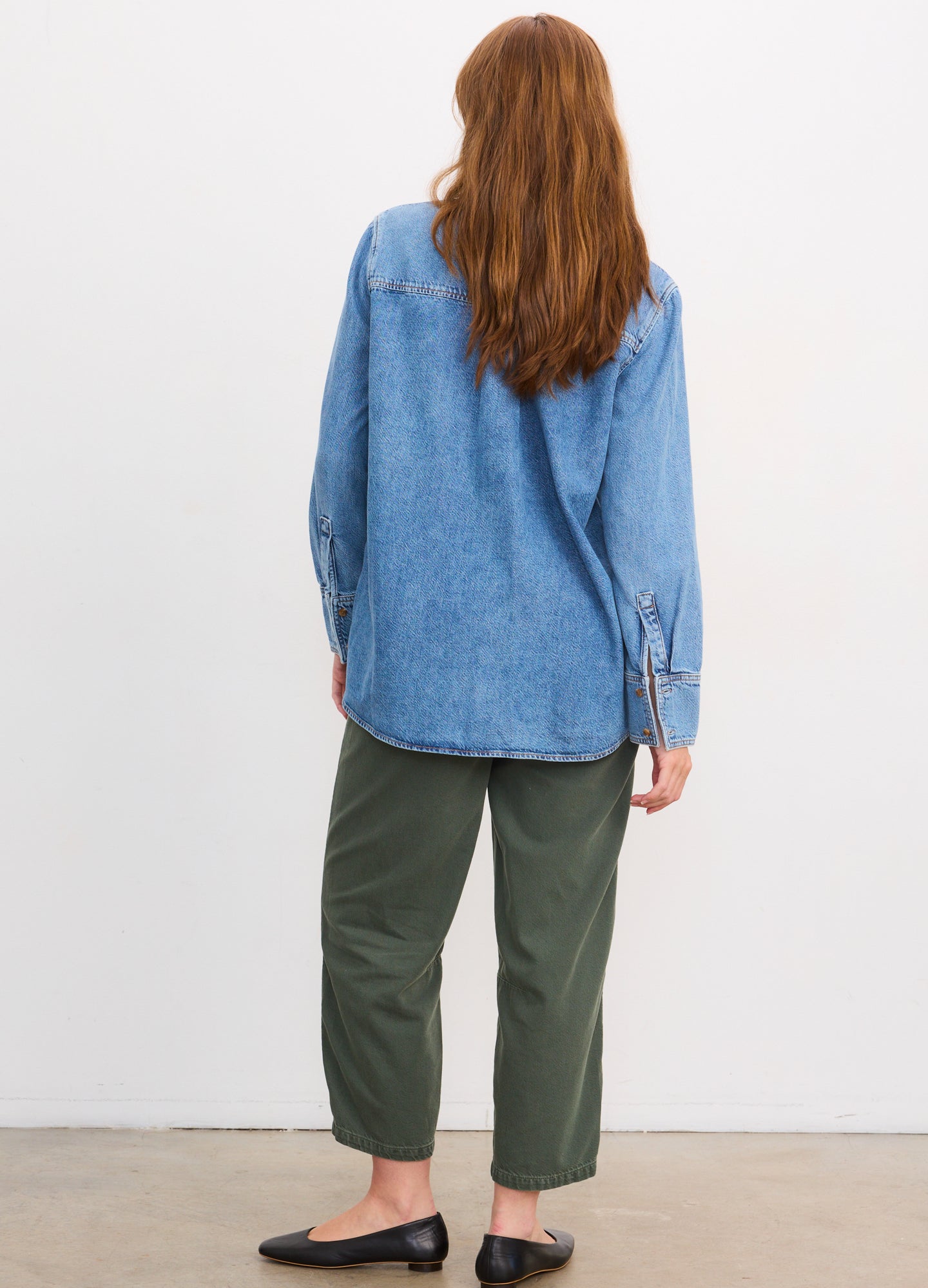 Light blue denim maternity shirt with long sleeves and relaxed boyfriend fit worn with olive green cropped pants and black.