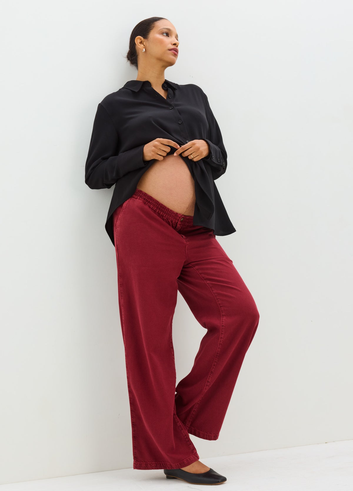 Burgundy maternity drapey denim pants with a relaxed wide-leg fit and stretchy waistband.