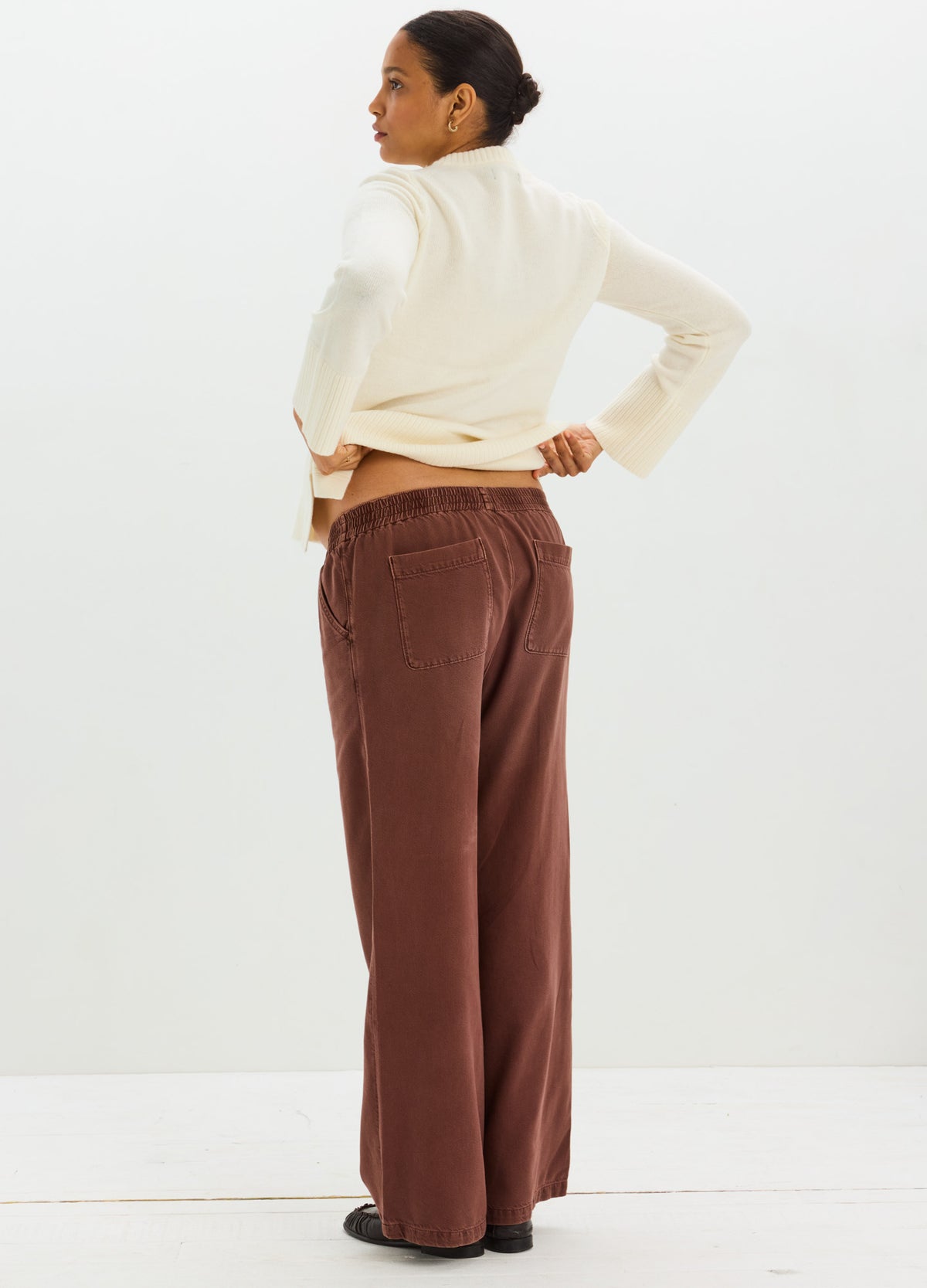 Brown drapey maternity denim pants with wide legs, worn with a cream long-sleeve top.