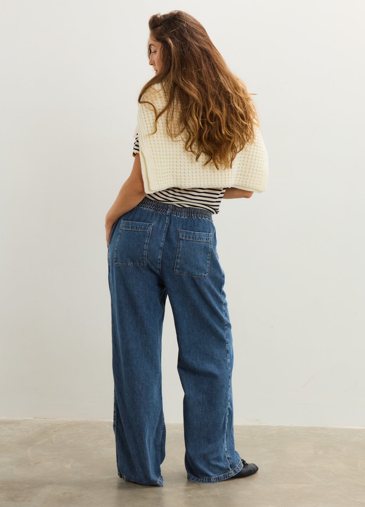 High-waisted dark blue denim maternity pants with a relaxed, wide-leg fit on a pregnant model.