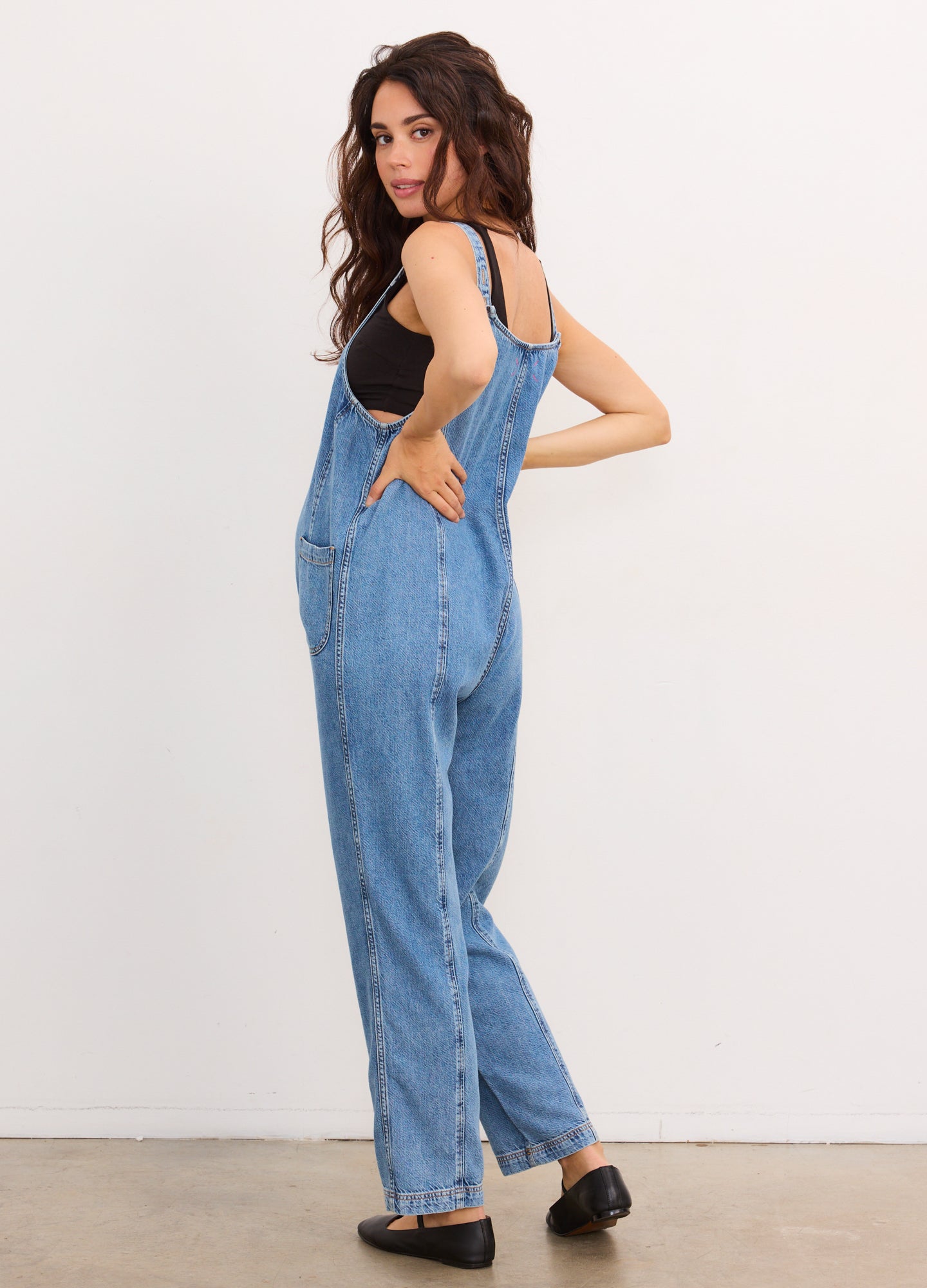 Light blue denim maternity jumpsuit with wide straps, relaxed legs, and side pockets.