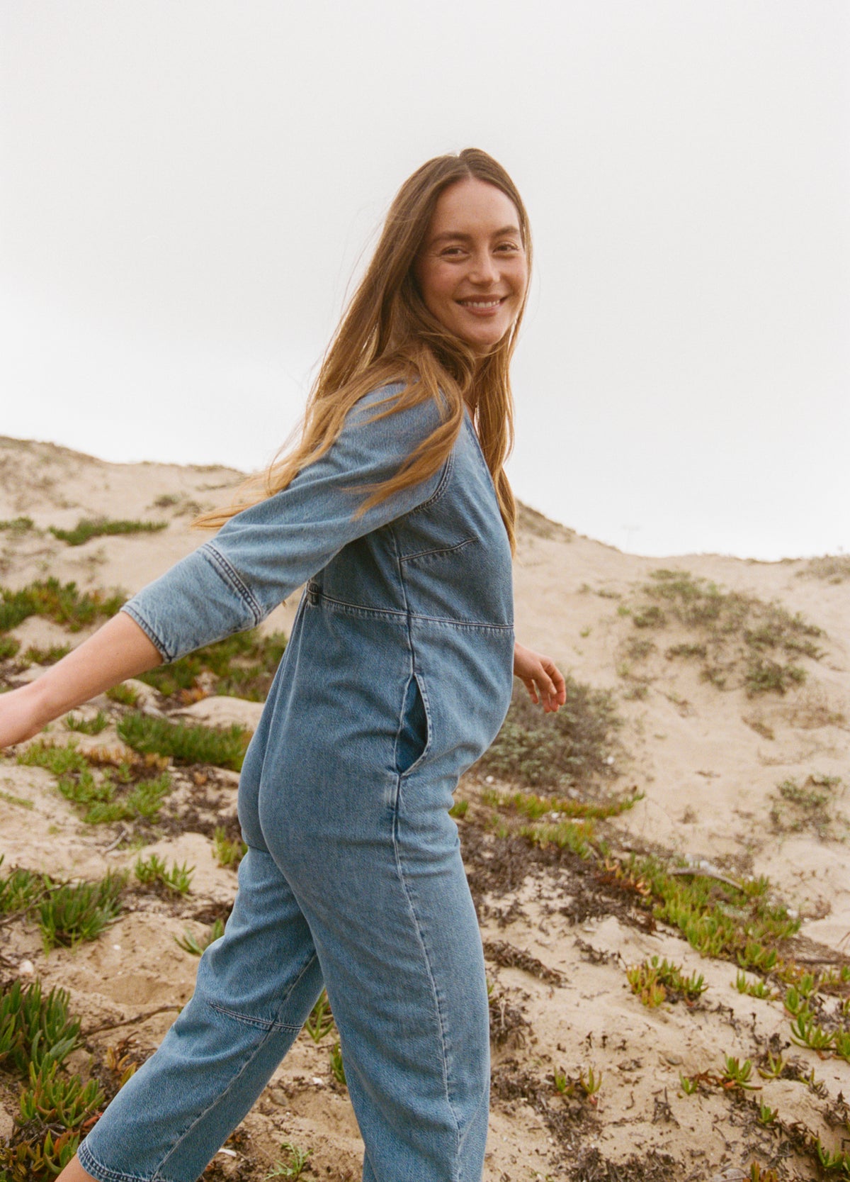 Light blue denim maternity jumpsuit with relaxed fit, long sleeves, and elastic waistband designed for pregnancy comfort.