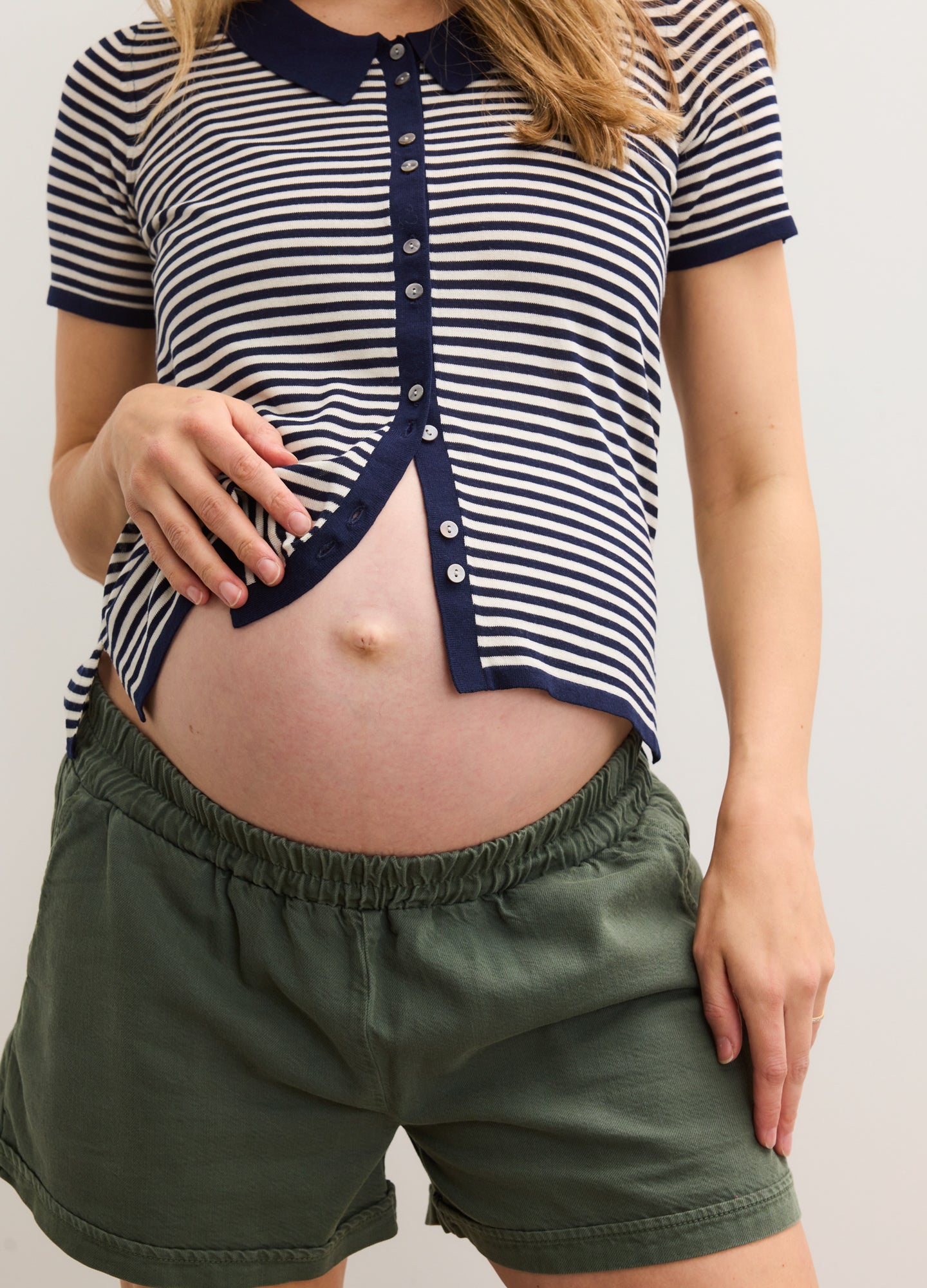 Dark green maternity shorts with elastic waistband designed for pregnant women, styled with a striped navy and white.
