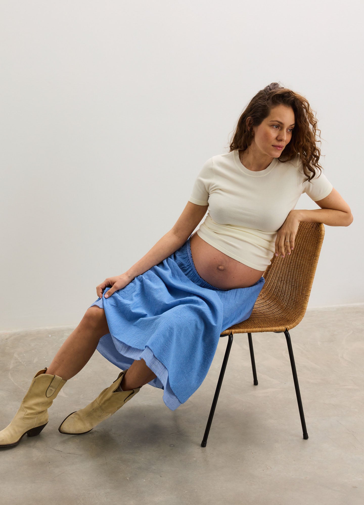 Light blue midi maternity skirt with a soft, flowy fabric, worn by a pregnant woman paired with a cream fitted t-shirt and.