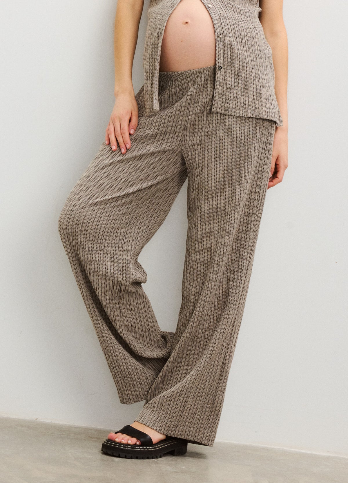 Taupe ribbed wide-leg maternity pants with elastic waist, styled with an open button-up shirt and sandals.