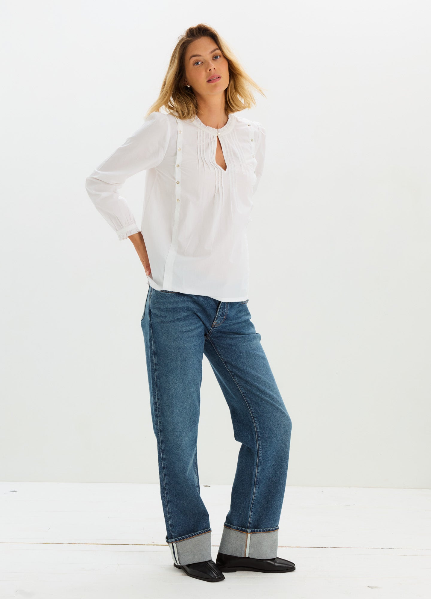 White maternity nursing blouse with three-quarter puff sleeves and keyhole neckline paired with cuffed blue jeans.