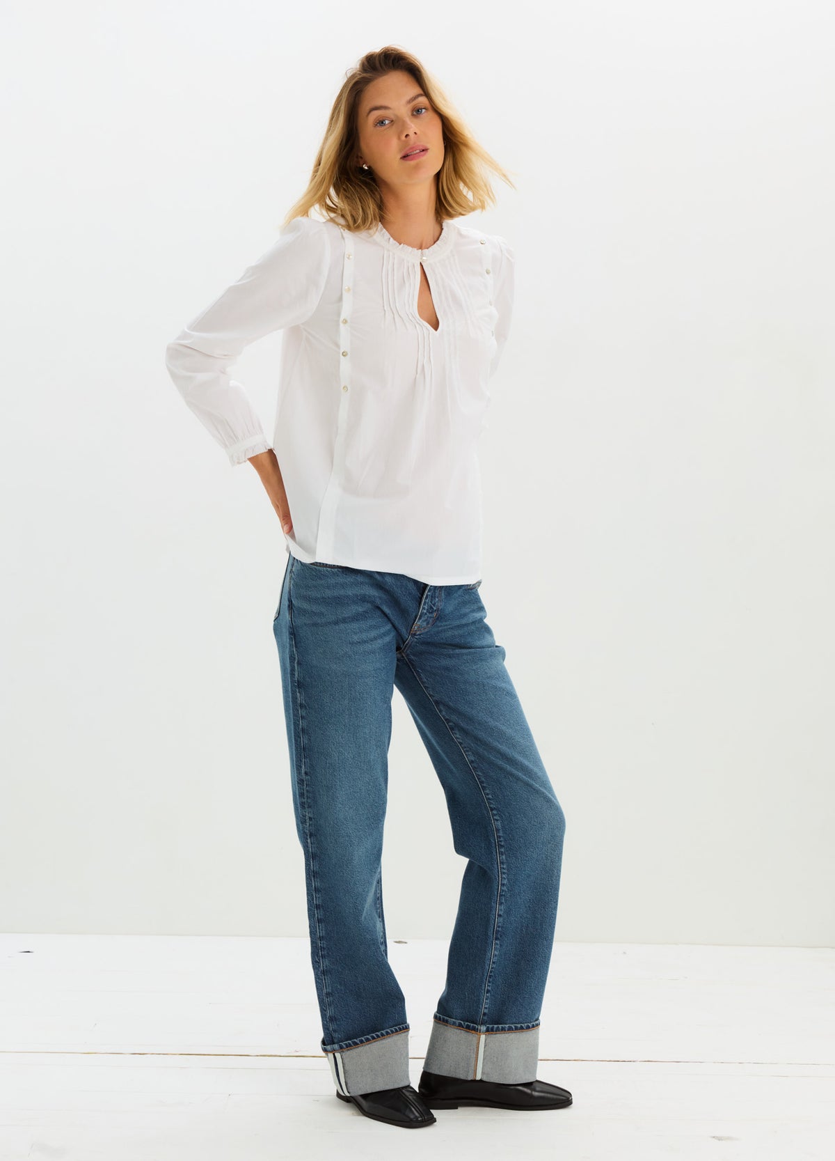 White maternity nursing blouse with three-quarter puff sleeves and keyhole neckline paired with cuffed blue jeans.