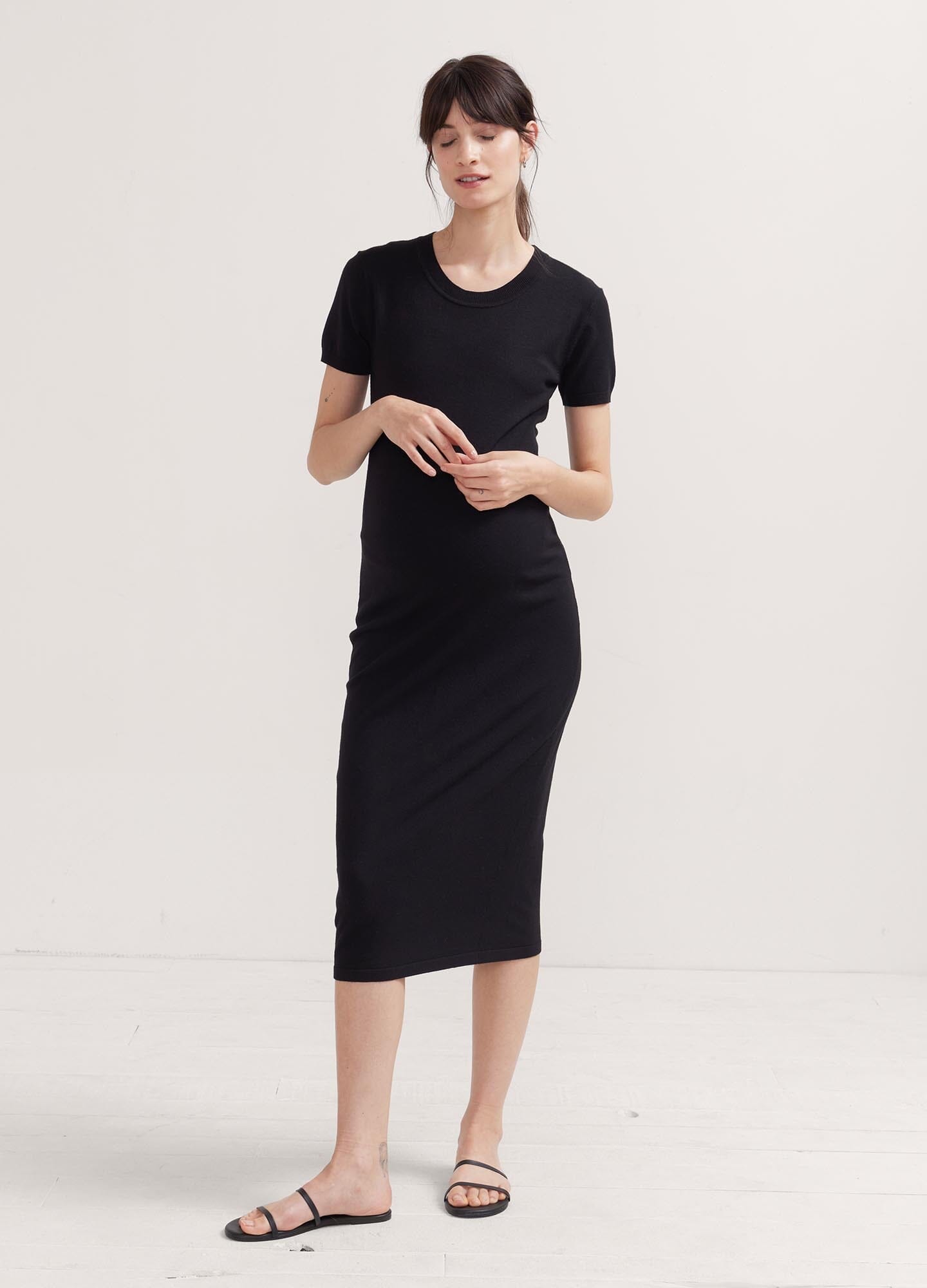 The Eliza Dress POS - Black short-sleeve maternity dress with nursing-friendly design and fitted silhouette, styled with tall black boots.