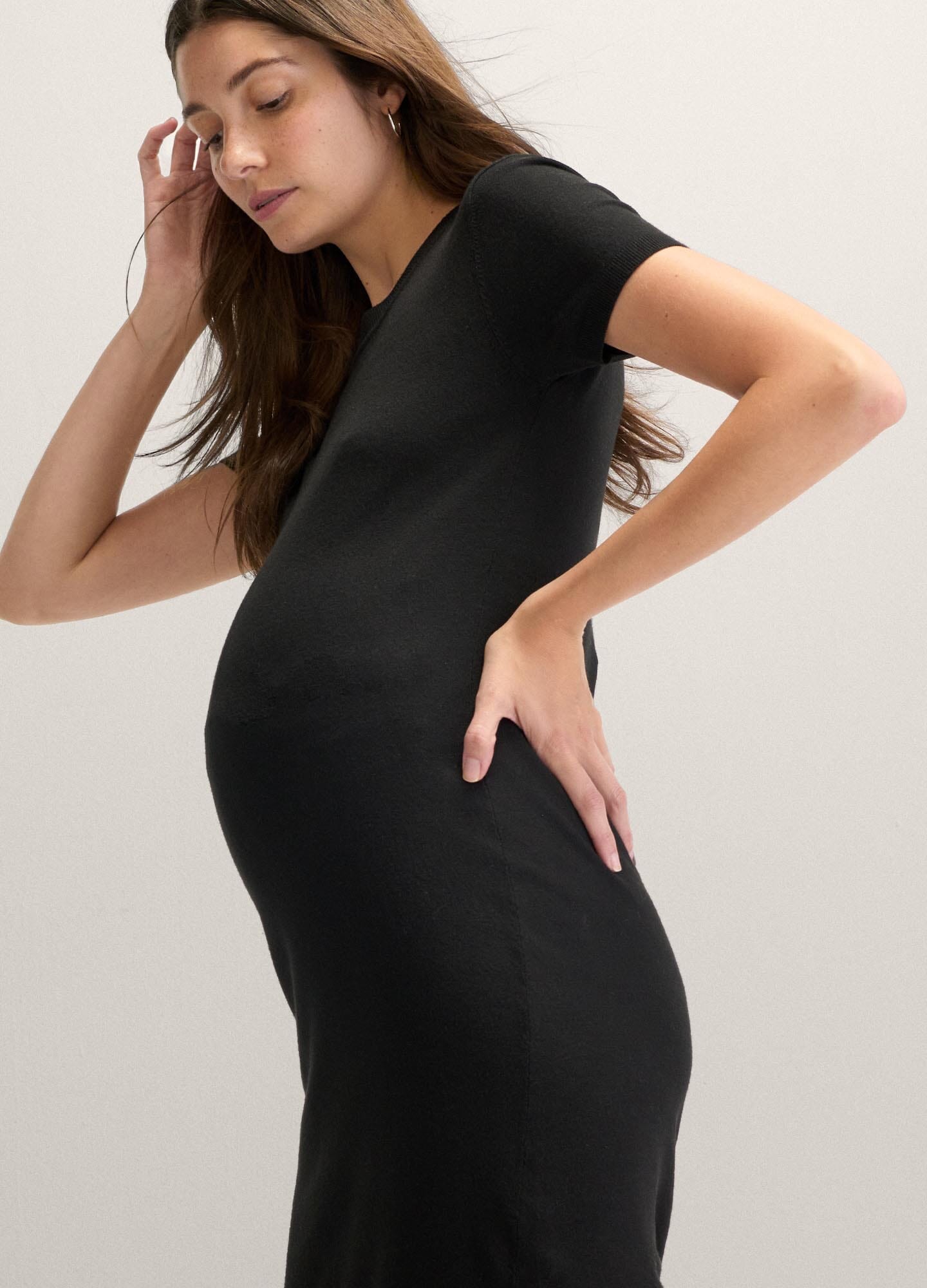 Black fitted knit maternity dress with short sleeves and round neckline, soft stretchy fabric.
