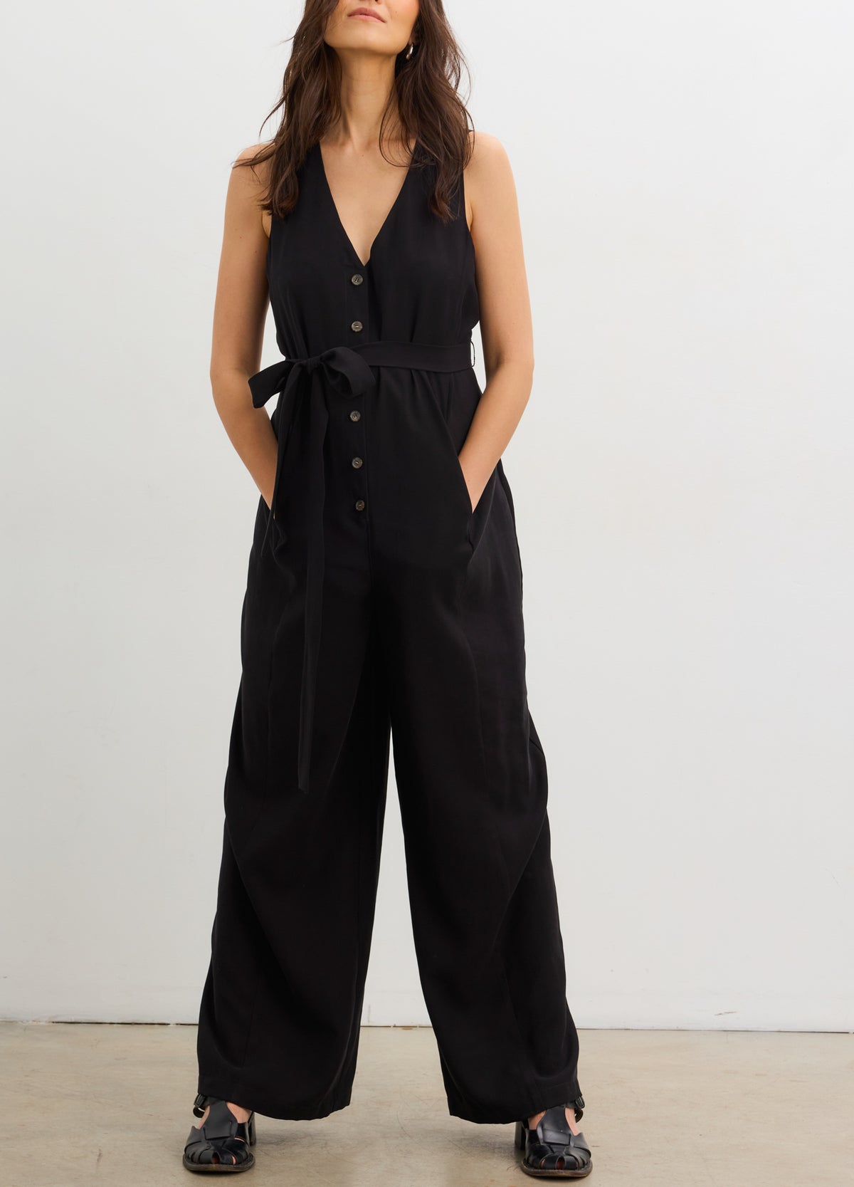 The Elliot Jumpsuit - Black sleeveless maternity jumpsuit with V-neck, nursing-friendly buttons, and a tie waist designed for pregnancy and.
