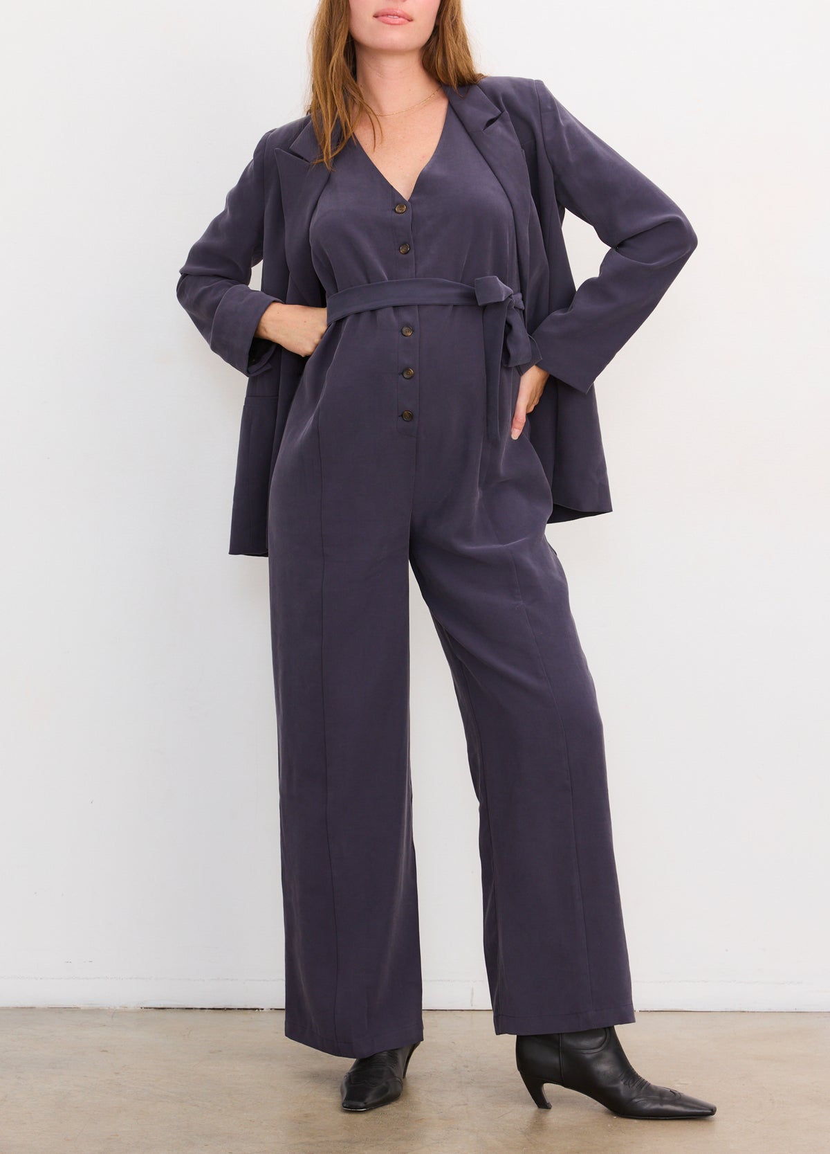 Navy blue maternity jumpsuit with long sleeves, button-up front, and wide-leg pants.