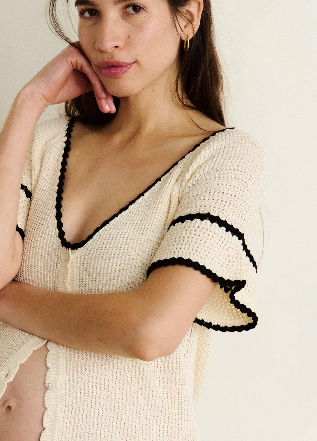 Cream crochet maternity cardigan with black edging and ruffle sleeves, soft knit texture.