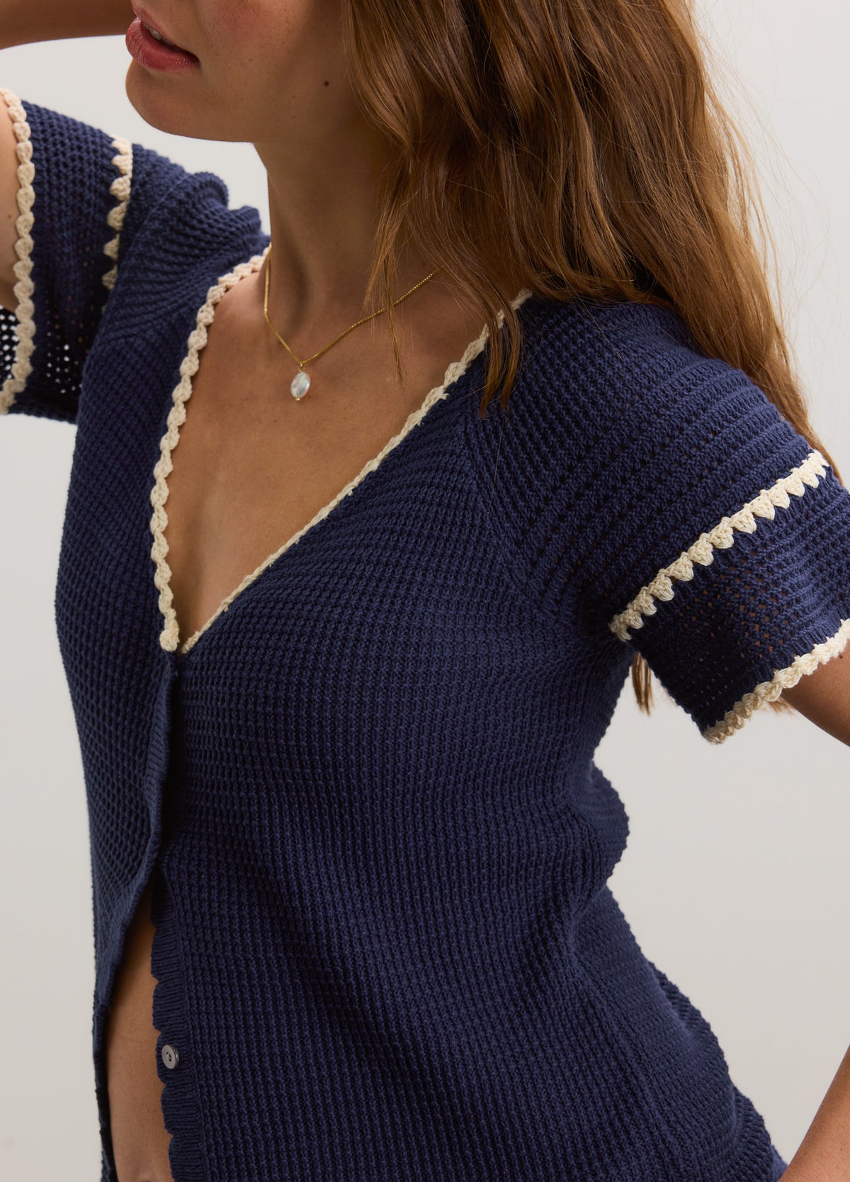 Navy blue crochet maternity cardigan with white trim and short sleeves, button-up front.