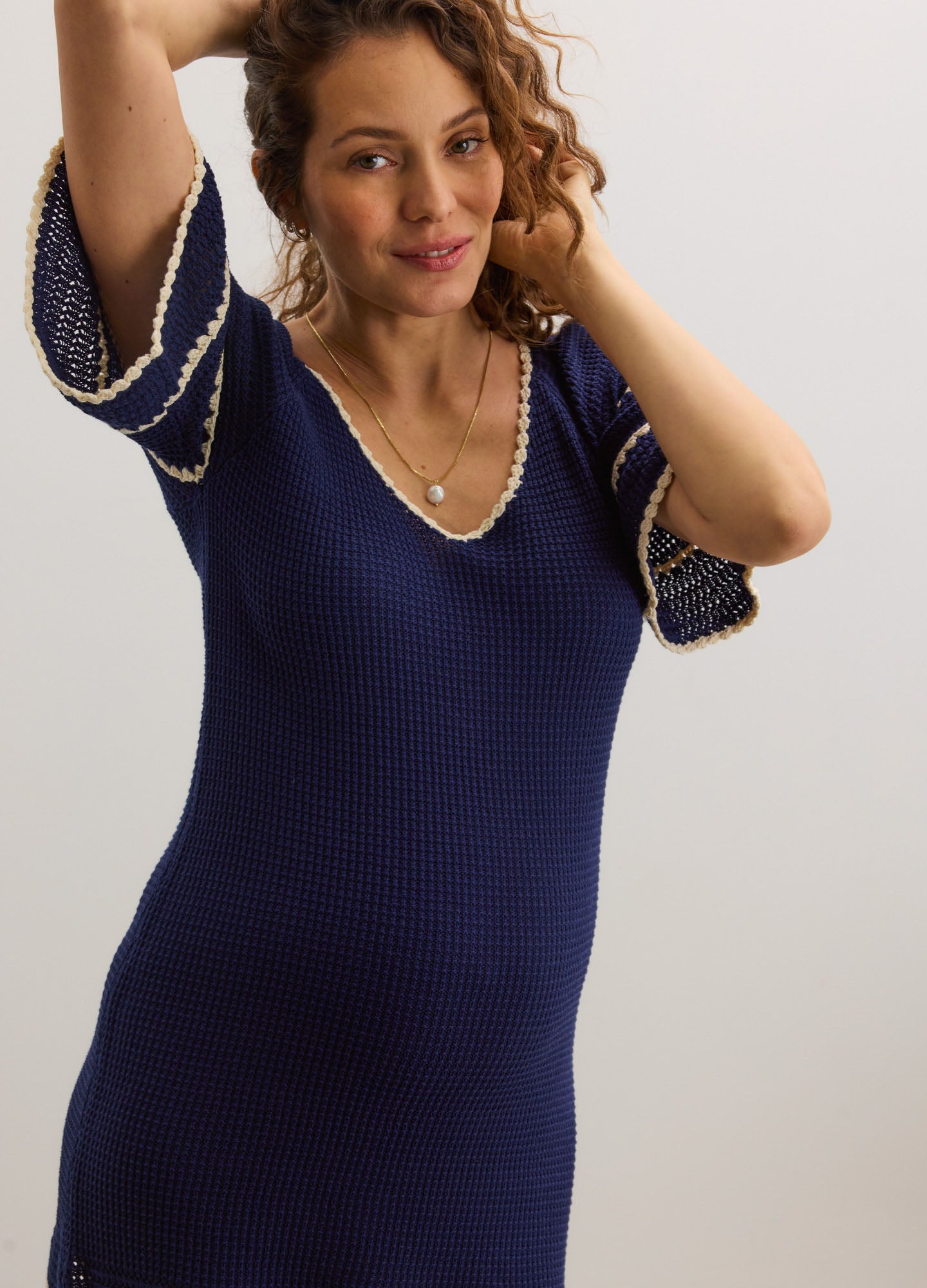 Navy blue maternity crochet dress with white trim on flared elbow sleeves and a scoop neckline.
