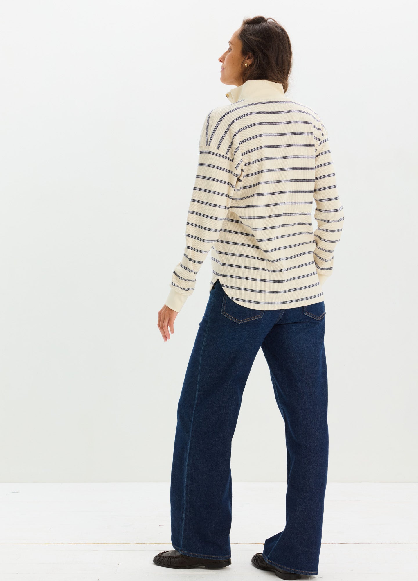 Cream and beige striped knit maternity nursing top with long sleeves and relaxed fit paired with dark blue jeans.
