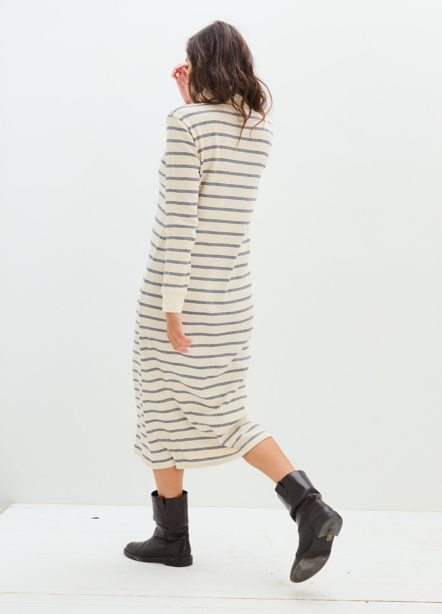 Cream and black striped long-sleeve waffle-knit maternity dress with a midi hem and relaxed fit worn with black ankle boots.