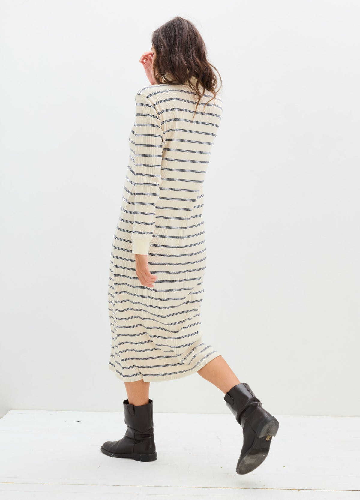 Cream and black striped long-sleeve waffle-knit maternity dress with a midi hem and relaxed fit worn with black ankle boots.