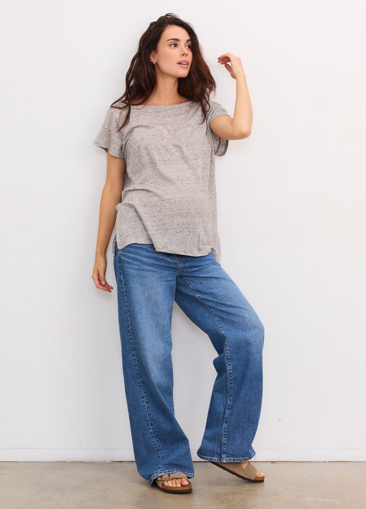 Light grey maternity linen tee with short sleeves, relaxed fit, and crew neck paired with wide-leg blue jeans.