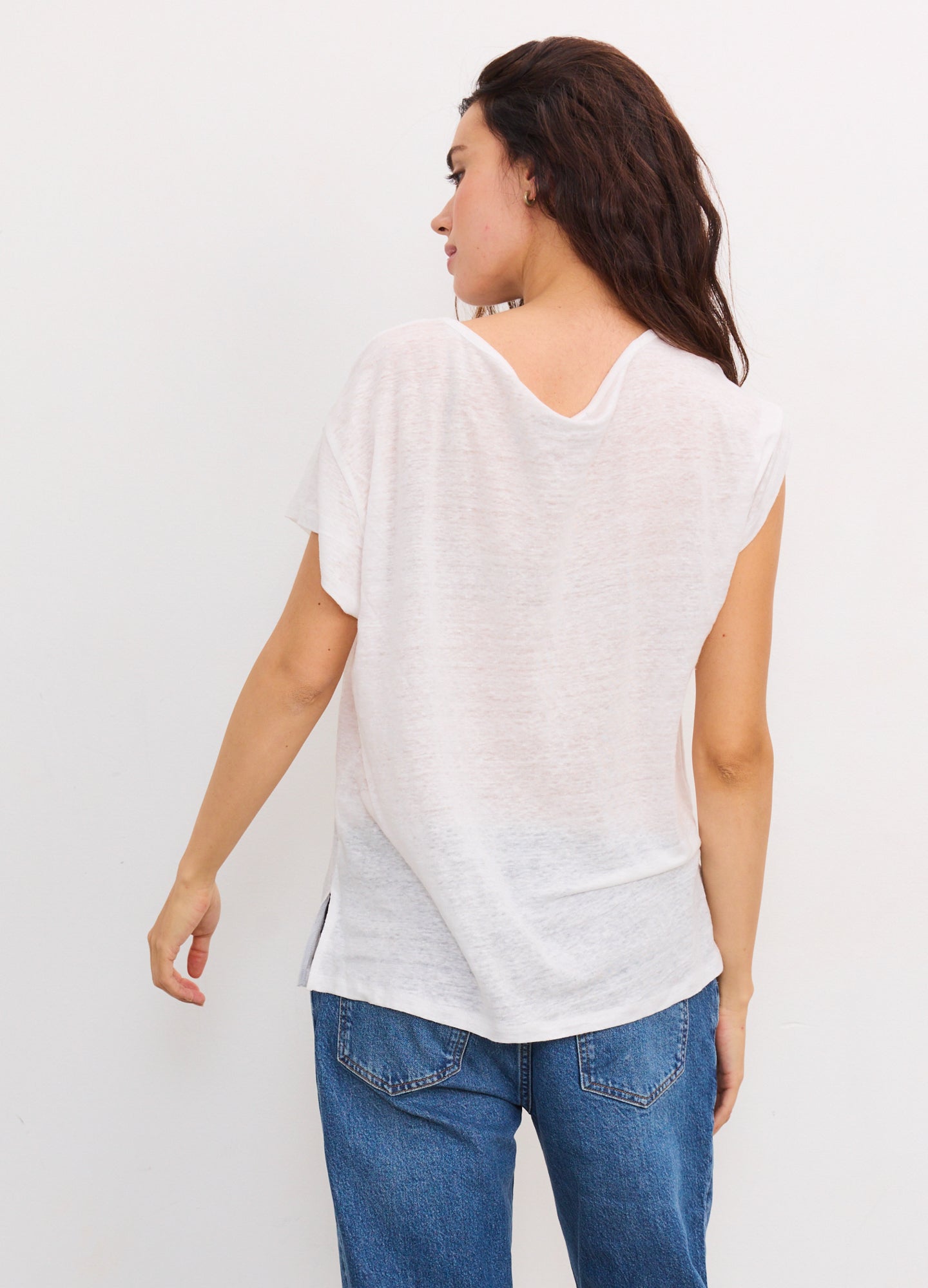 Soft white linen maternity tee with short sleeves and a relaxed fit, styled with casual blue jeans.