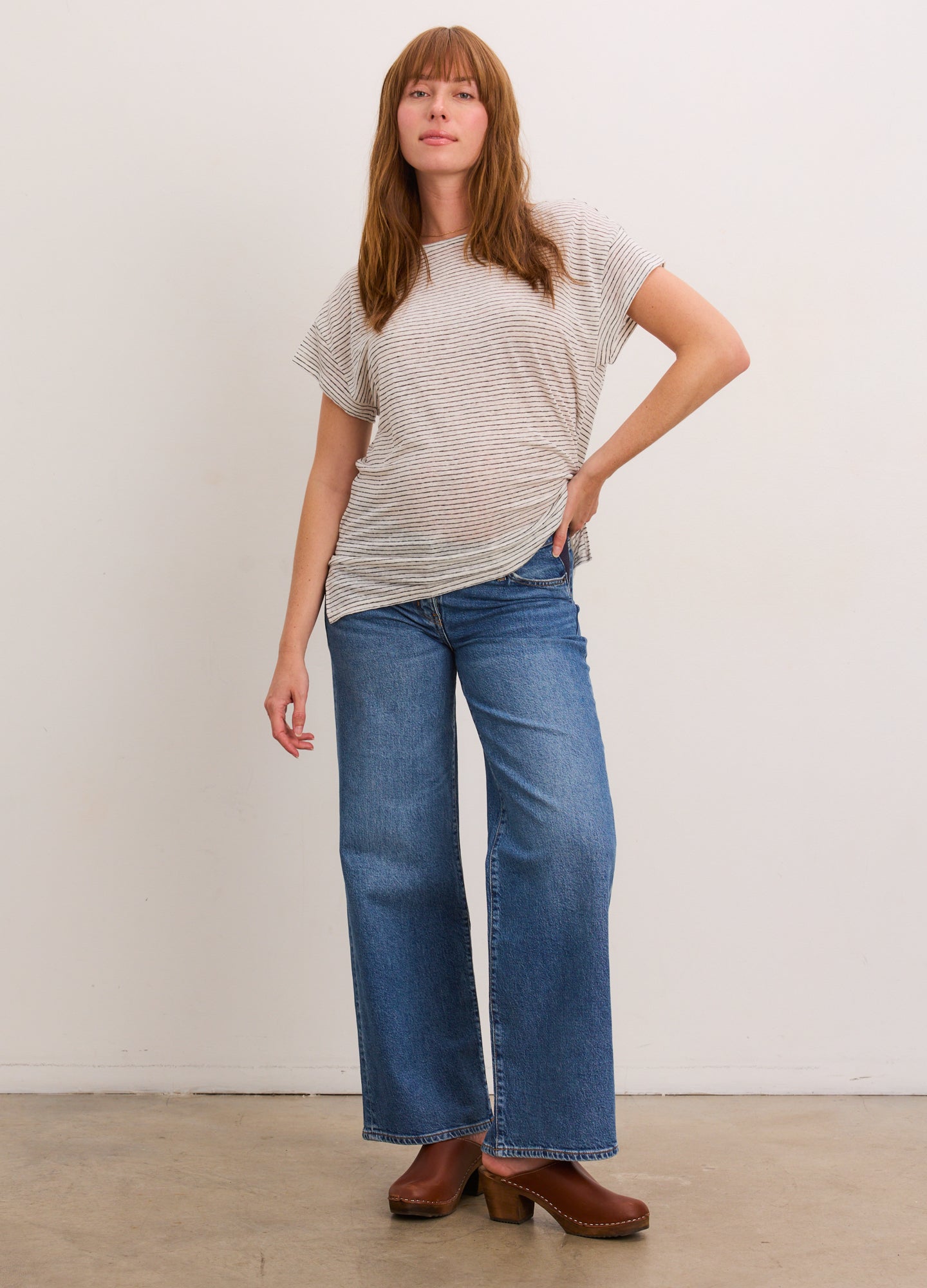 Grey and white striped short-sleeve linen tee with a relaxed fit modeled with blue wide-leg jeans.