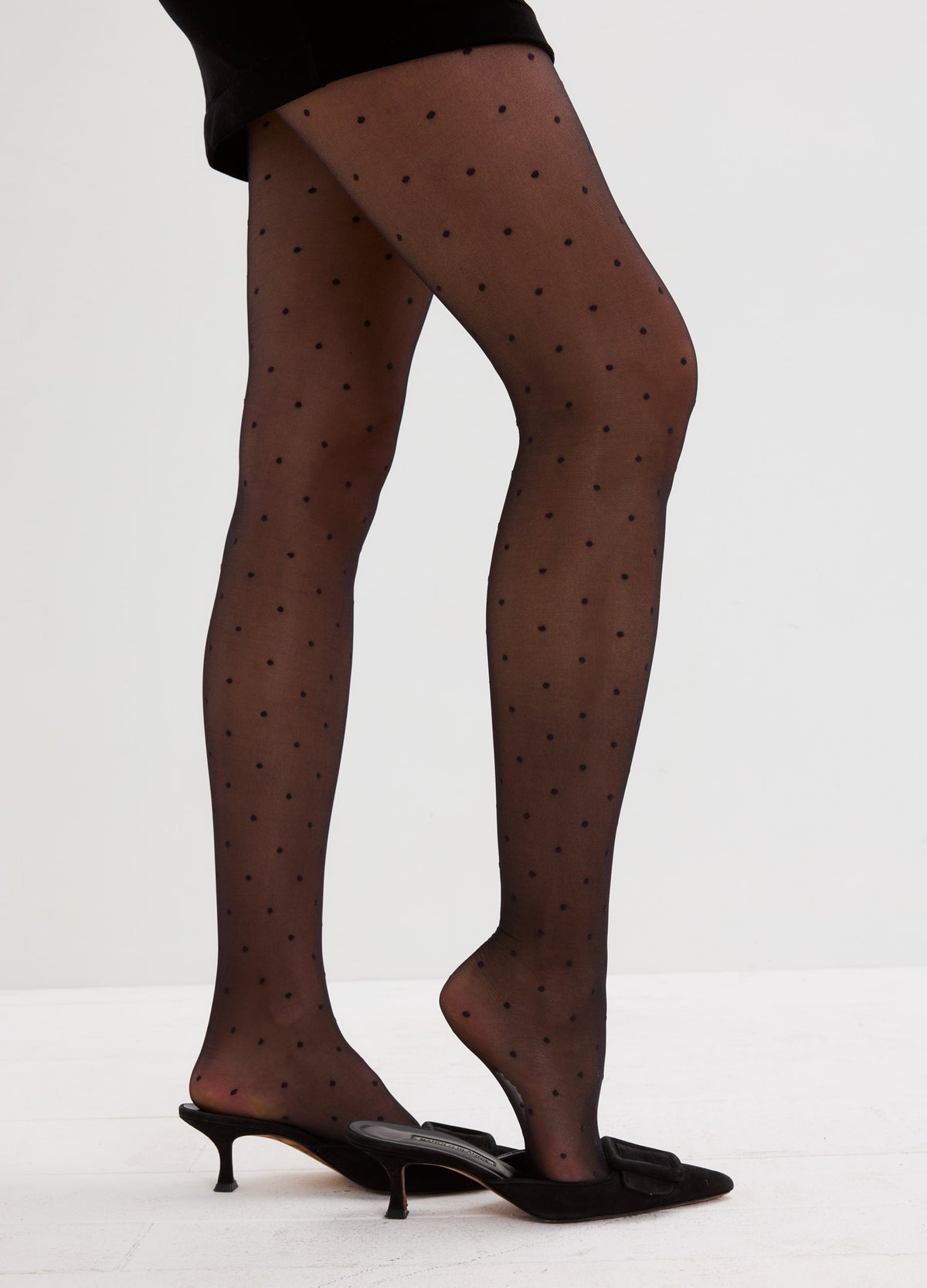 Sheer black tights with a delicate all-over dot pattern, paired with black pointed heels.