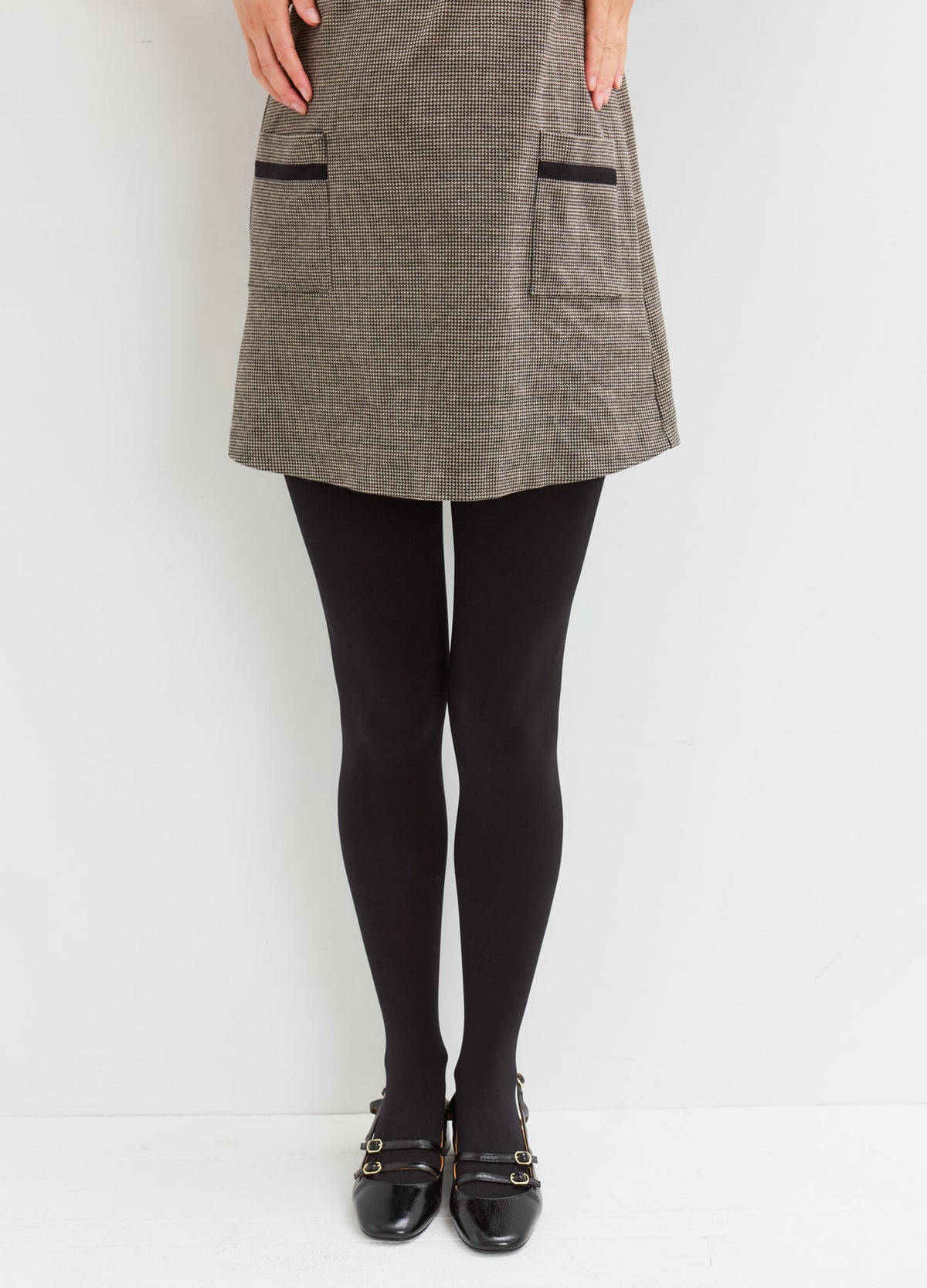 Matte black sheer tights paired with a textured gray skirt and black flats.