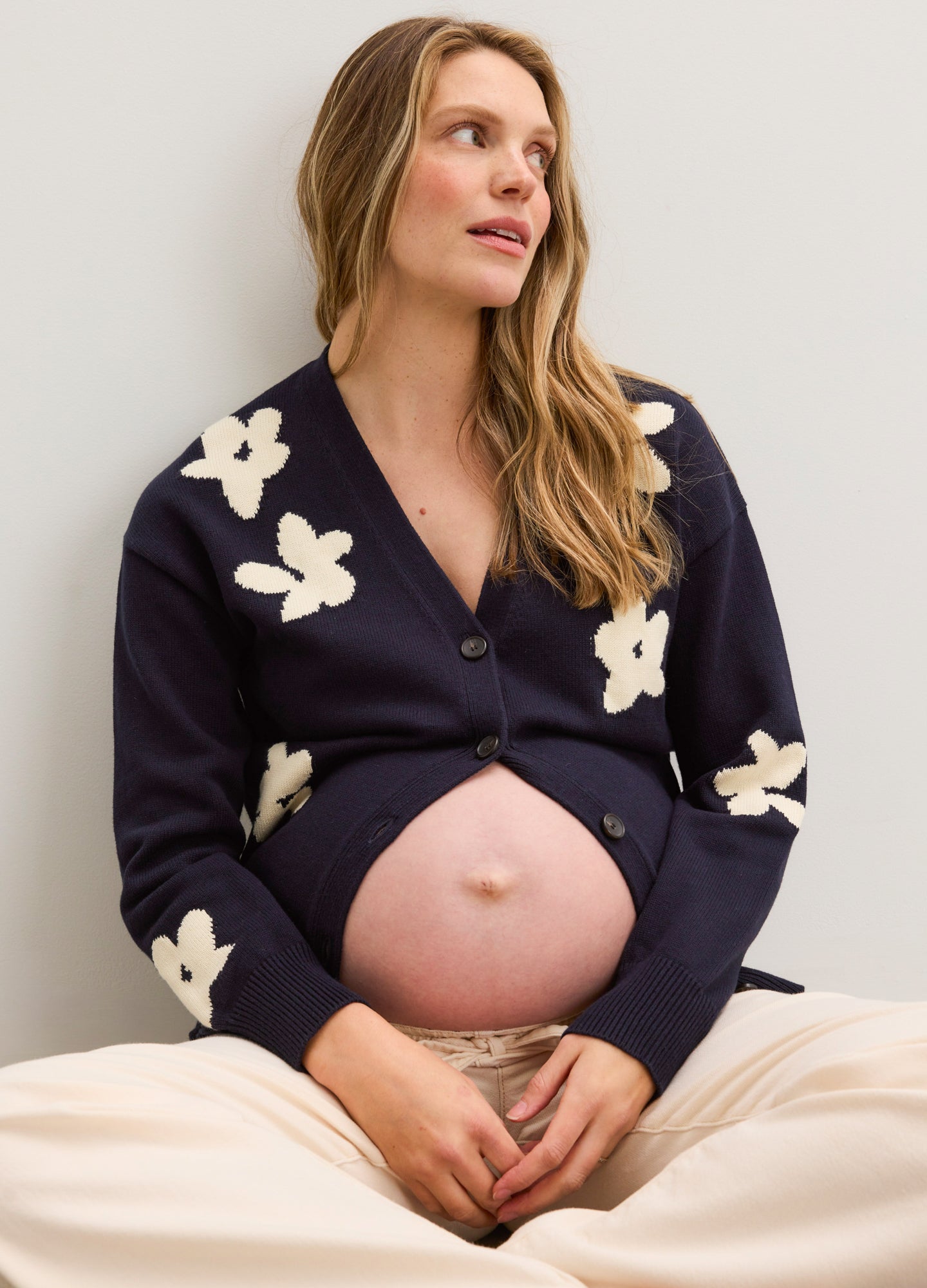 Navy oversized cardigan with cream floral jacquard pattern, buttoned over pregnant belly, long sleeves.