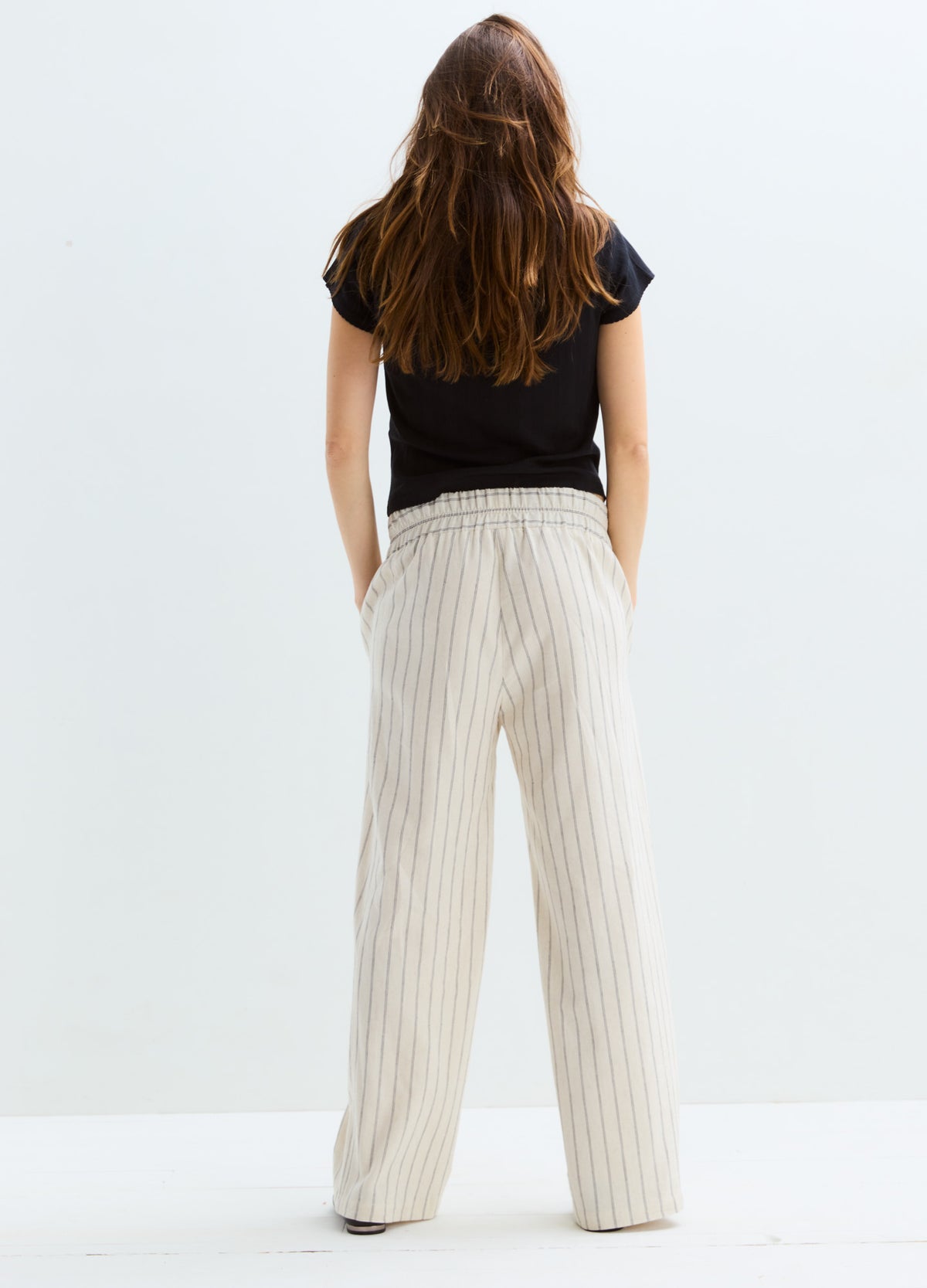 Beige wide-leg maternity pants with thin vertical stripes and adjustable waistband.