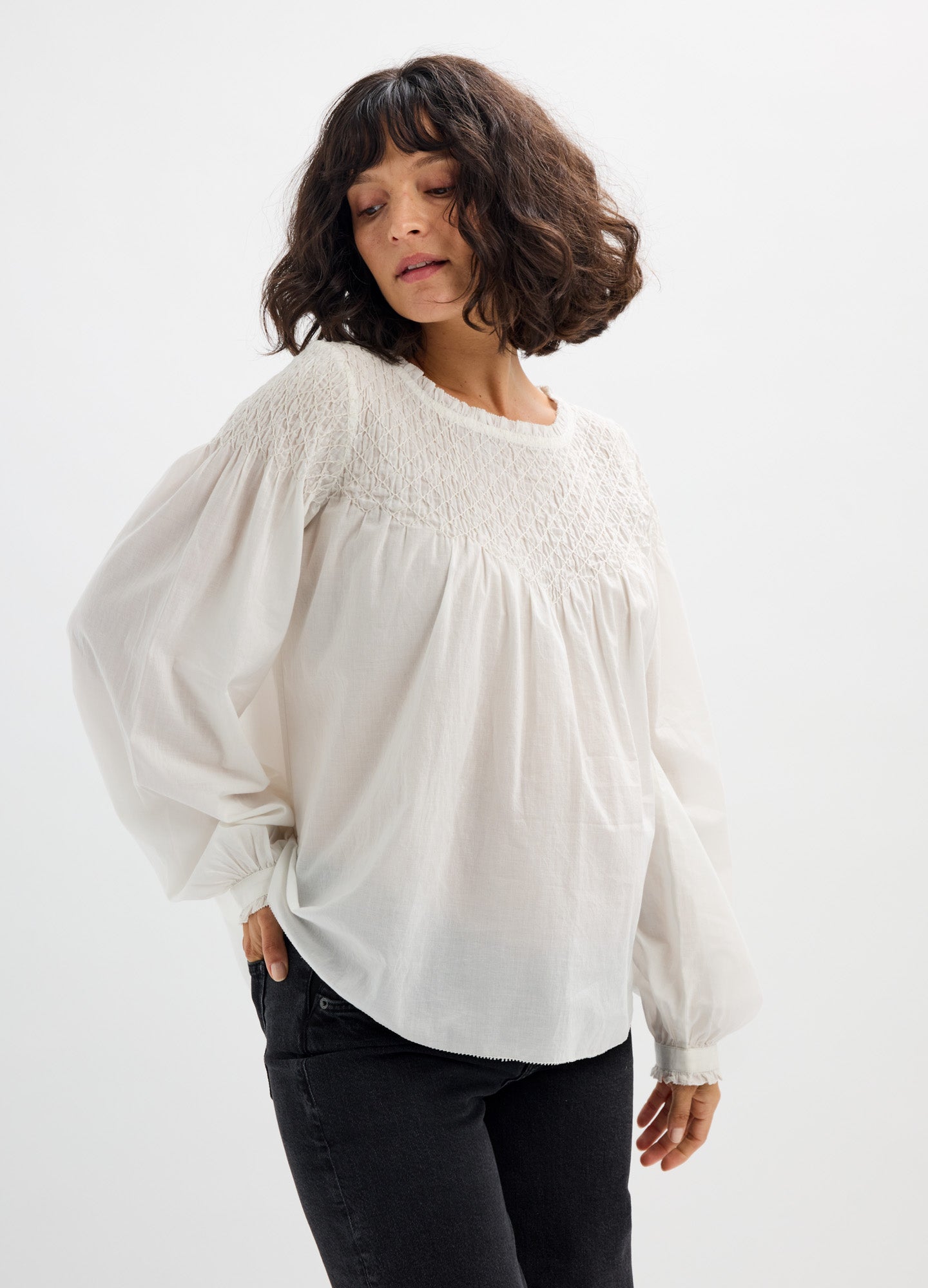White maternity blouse with smocked neckline and billowy long sleeves, loose fit for pregnancy comfort.