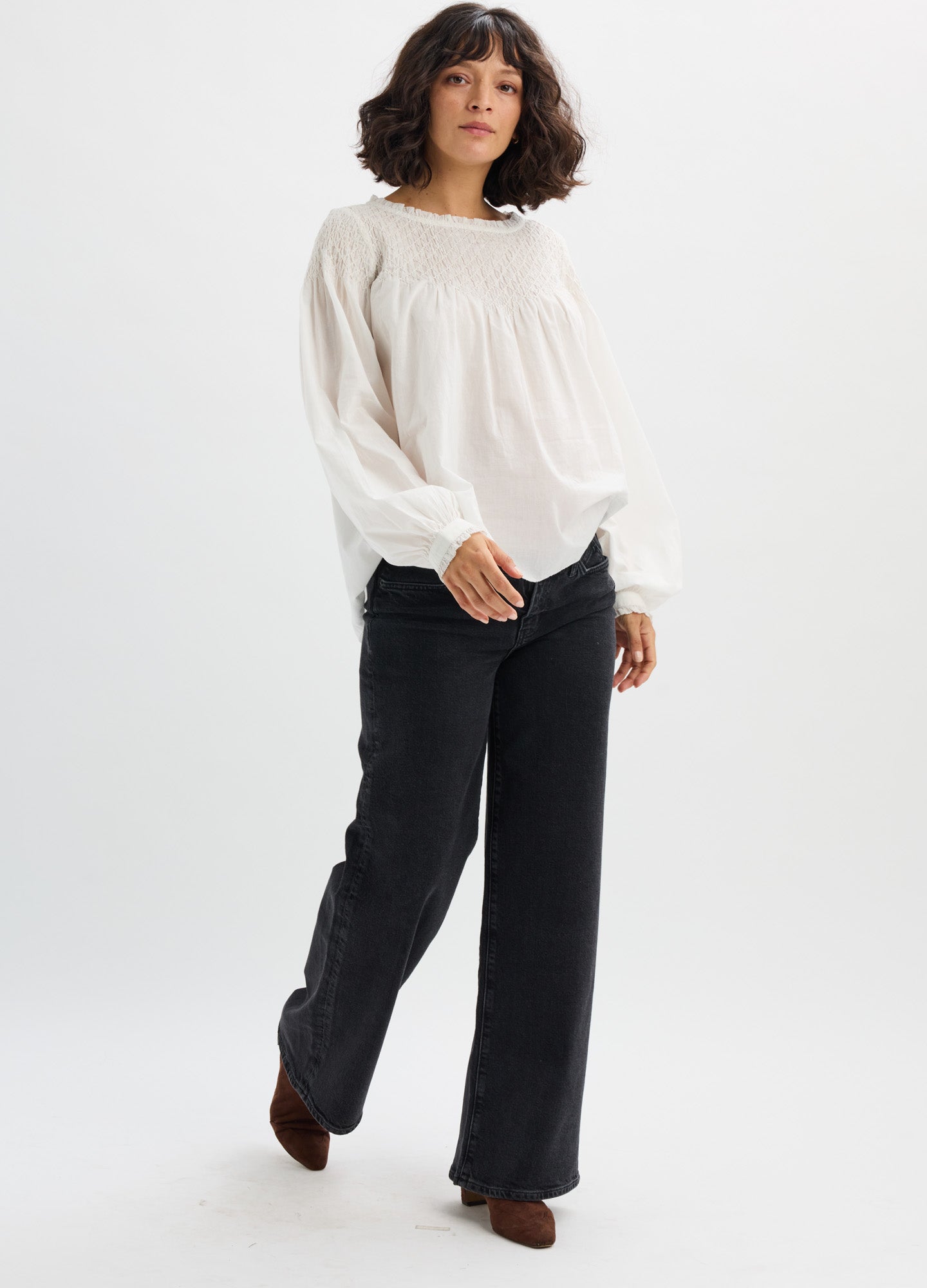 Cream-colored maternity blouse with long sleeves and gathered neckline, paired with black wide-leg pants.