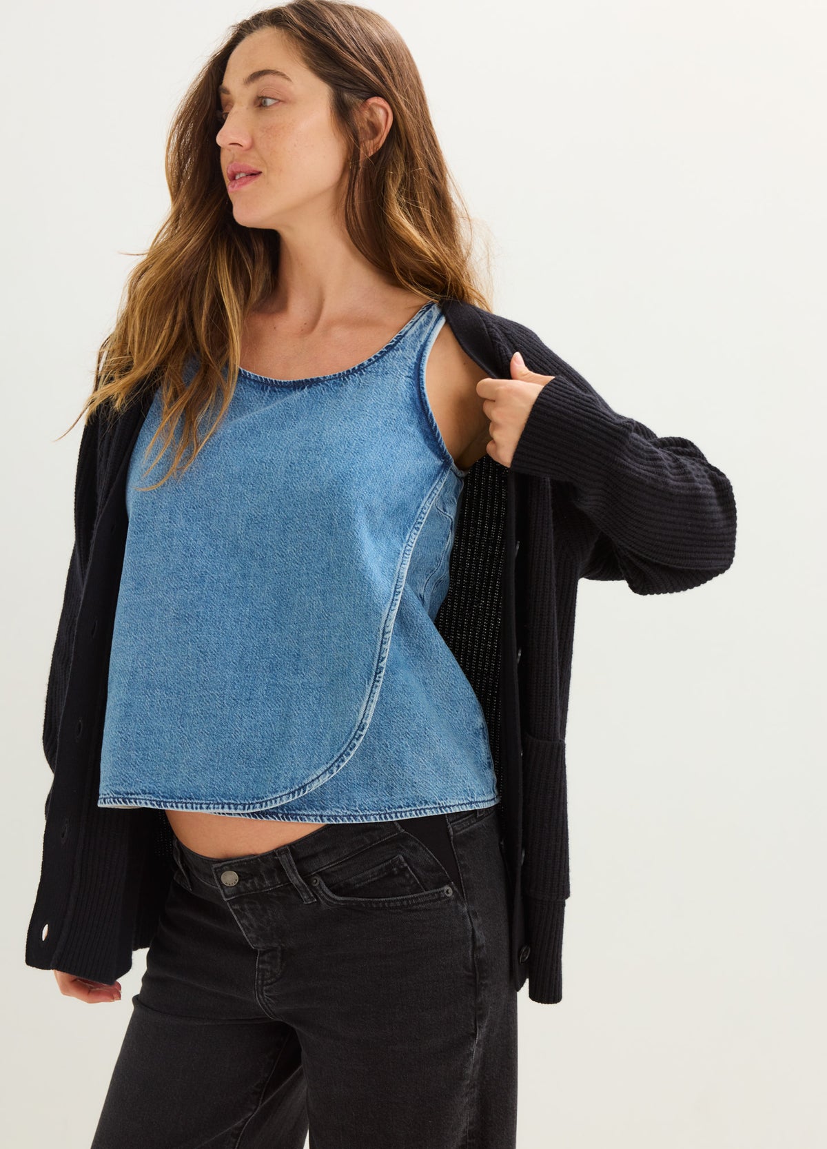 Light blue sleeveless denim maternity top with side button detail and rounded hem.
