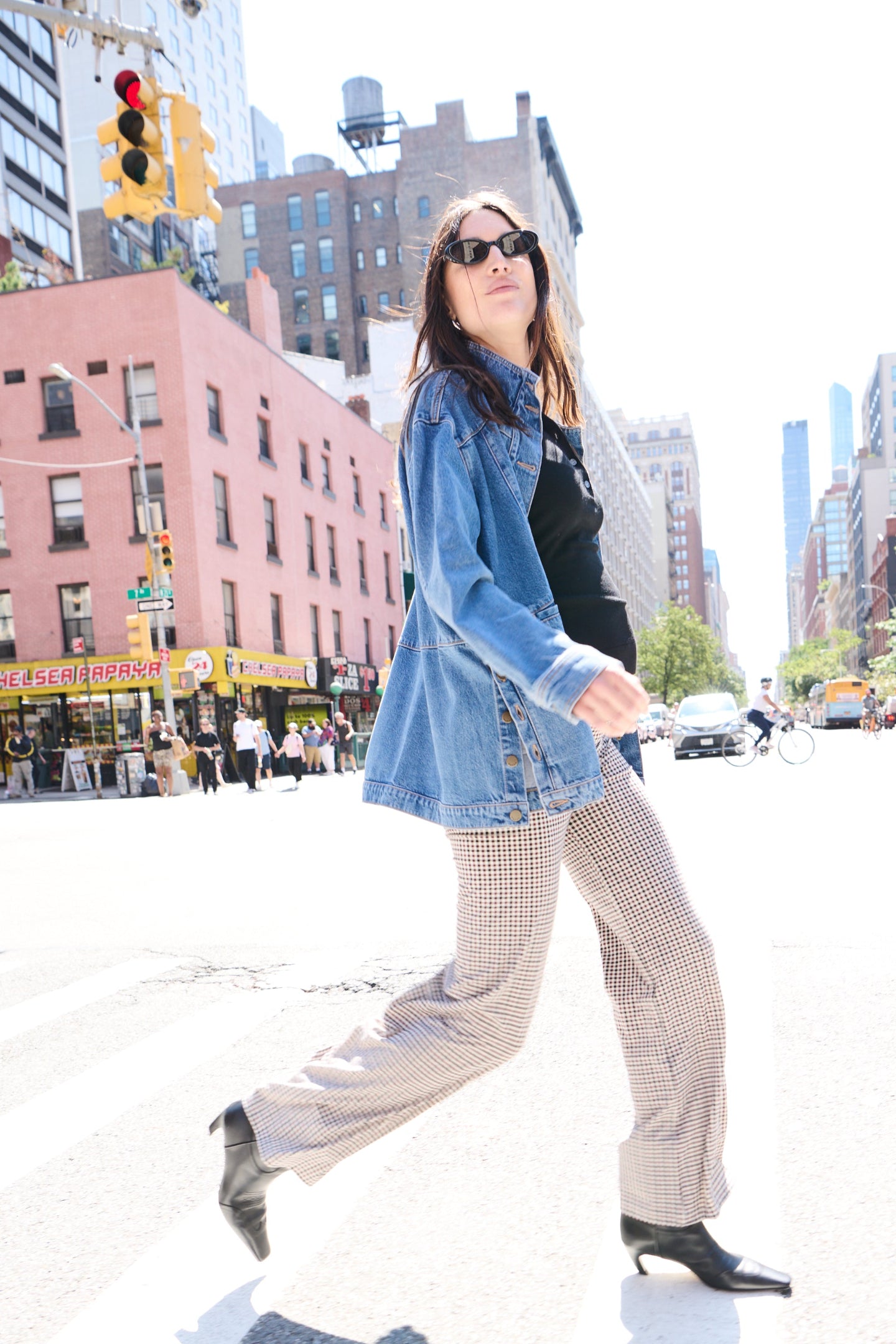 Light beige maternity pants with straight legs, paired with a black top and denim jacket on a pregnant model walking.