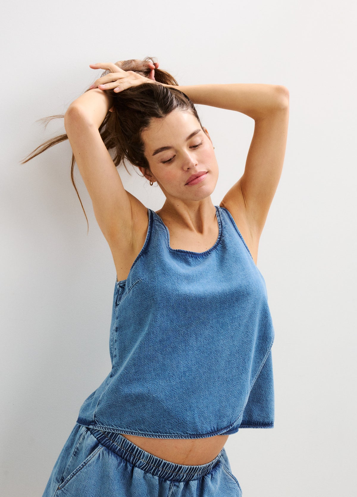 Sleeveless blue denim maternity top with loose fit and round neckline, showing baby bump.
