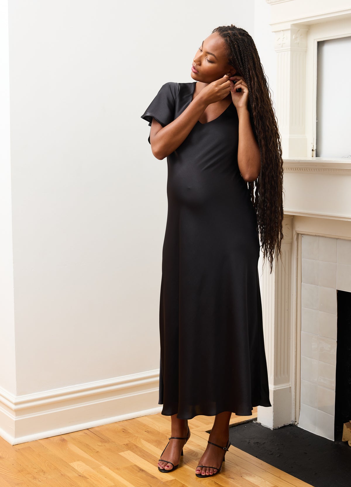 Black maternity dress with short sleeves and flowing skirt, styled for pregnant women.