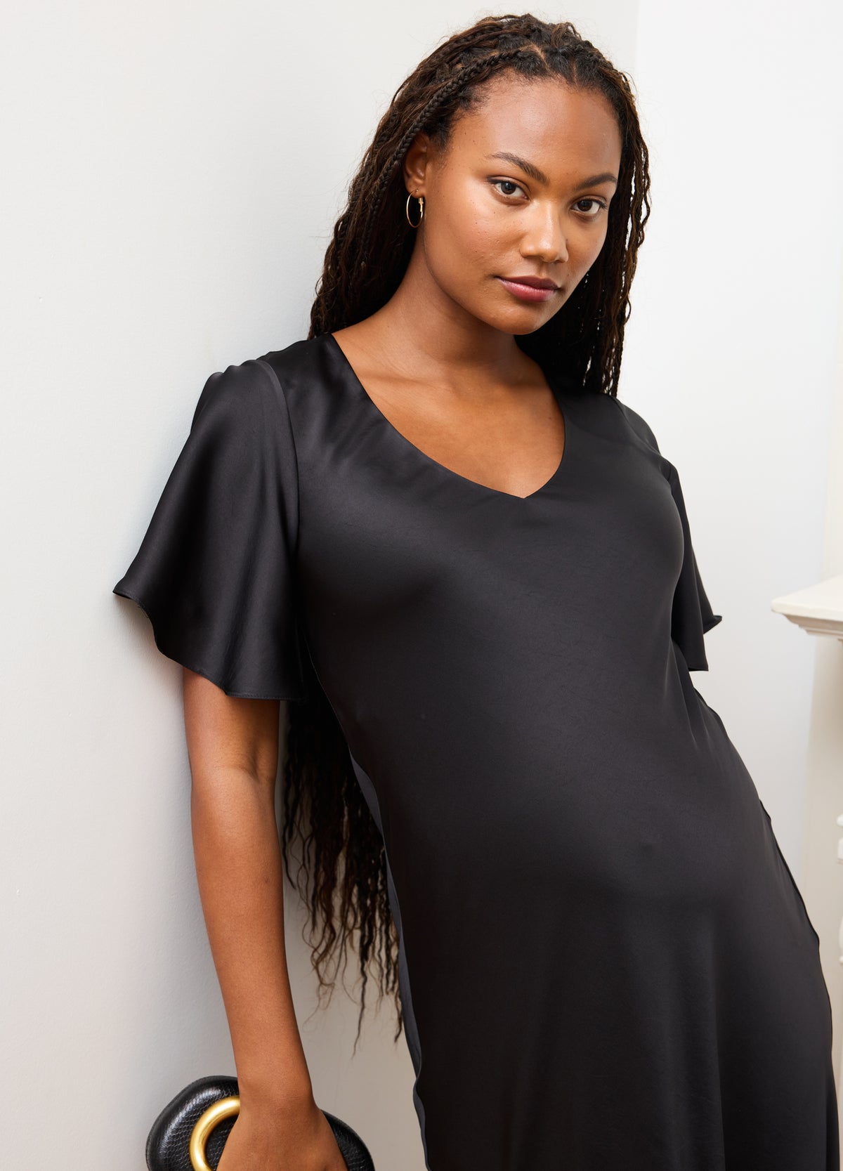 Black satin maternity dress with flutter sleeves and a V-neckline, designed for pregnant women.