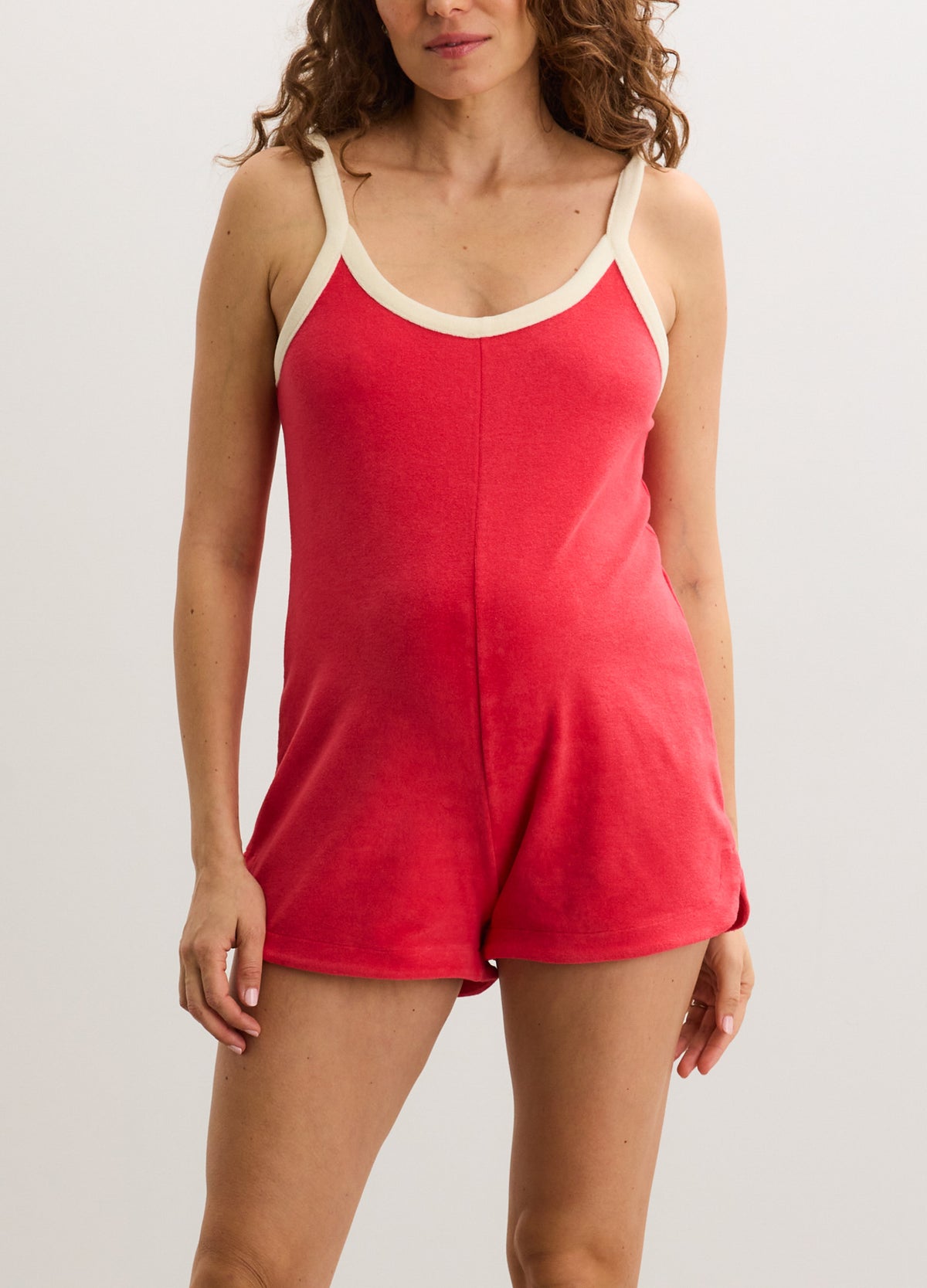 Red sleeveless maternity romper with cream trim, scoop neckline, and relaxed fit.