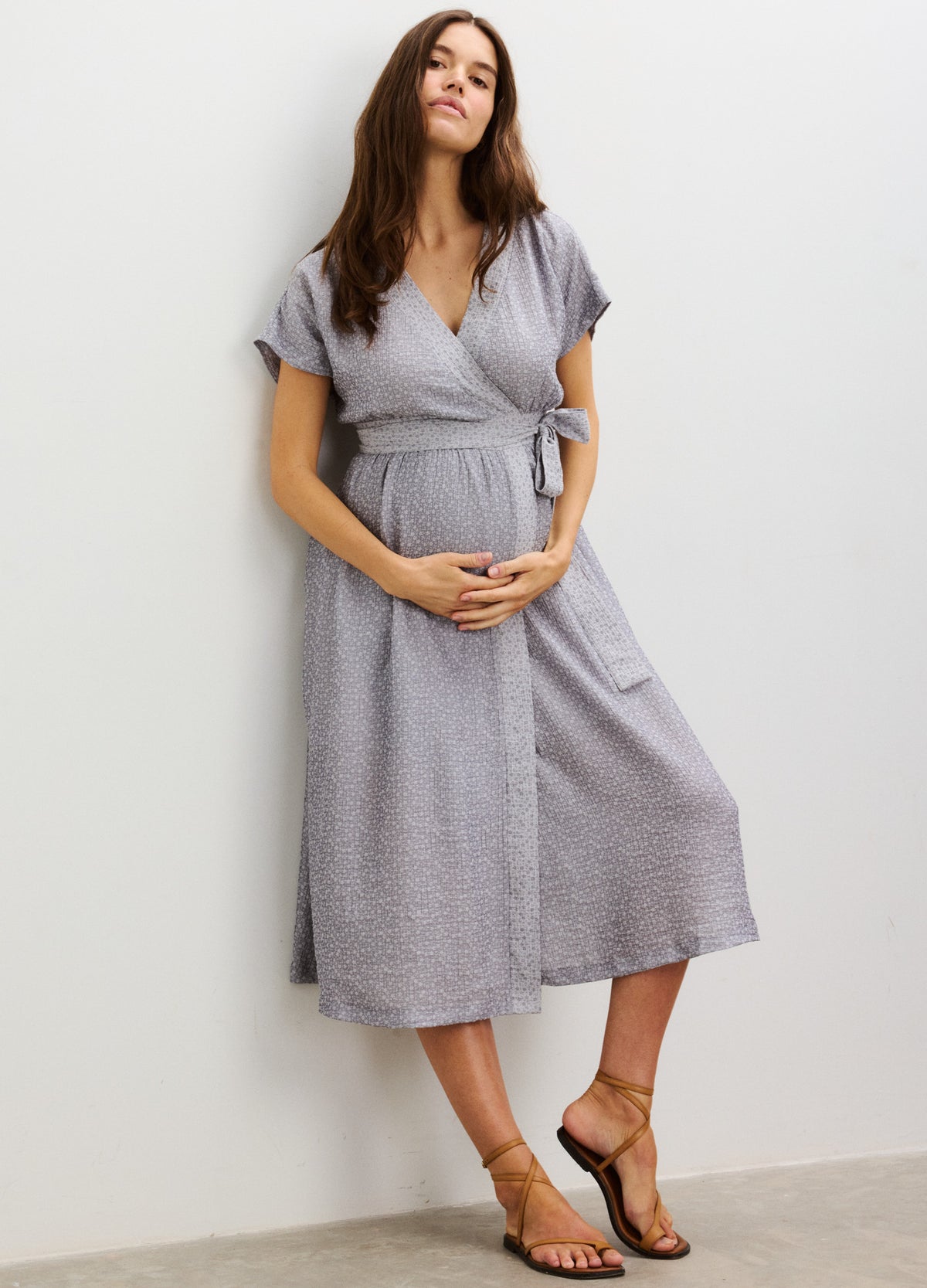 Light gray short-sleeve maternity dress with wrap v-neck, empire waist, and midi length.