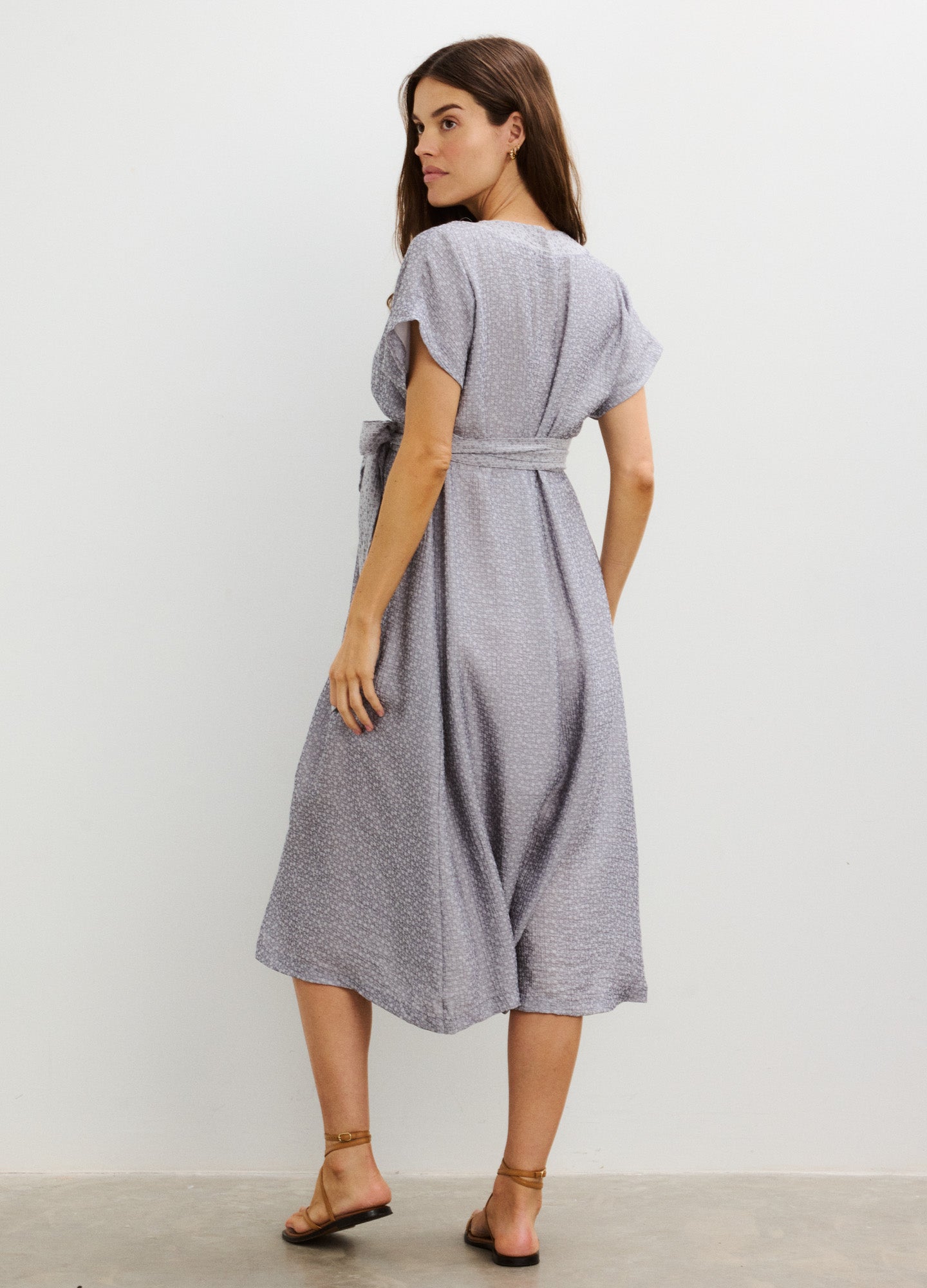 Light grey midi maternity dress with short sleeves, V-neck, belted waist, and flowing skirt.