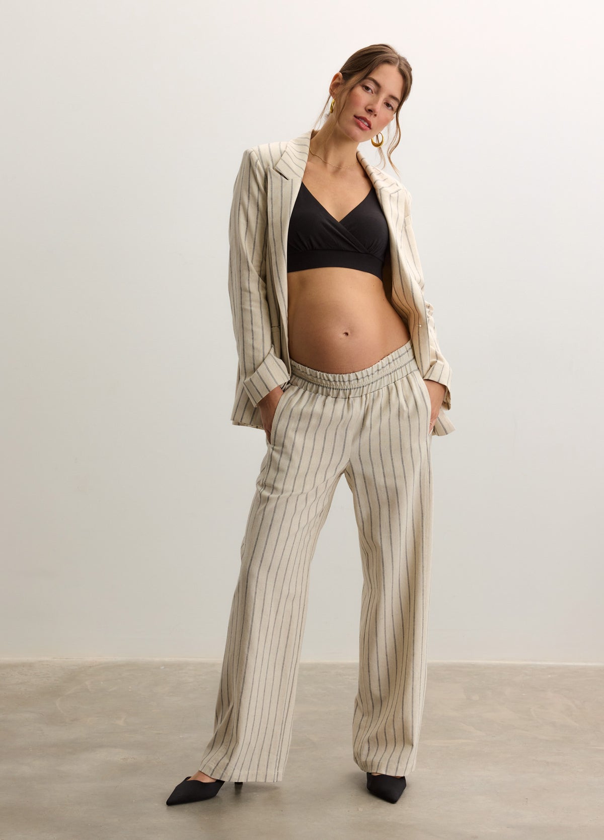 Beige pinstripe maternity blazer and matching wide-leg tailored trousers with a soft, relaxed fit over a black cropped top.