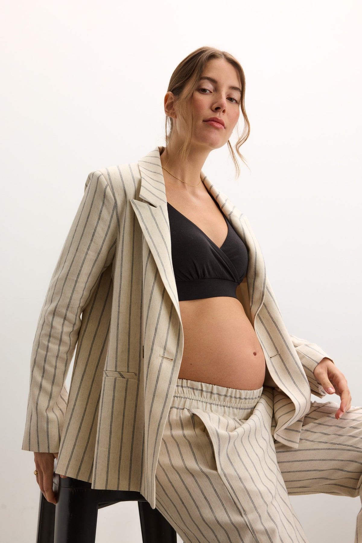 Cream and beige striped tailored maternity blazer with relaxed fit, worn open over black bra.