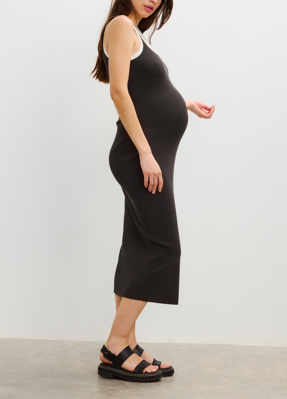 Black sleeveless midi maternity dress with fitted silhouette, round neckline, and soft stretchy fabric.