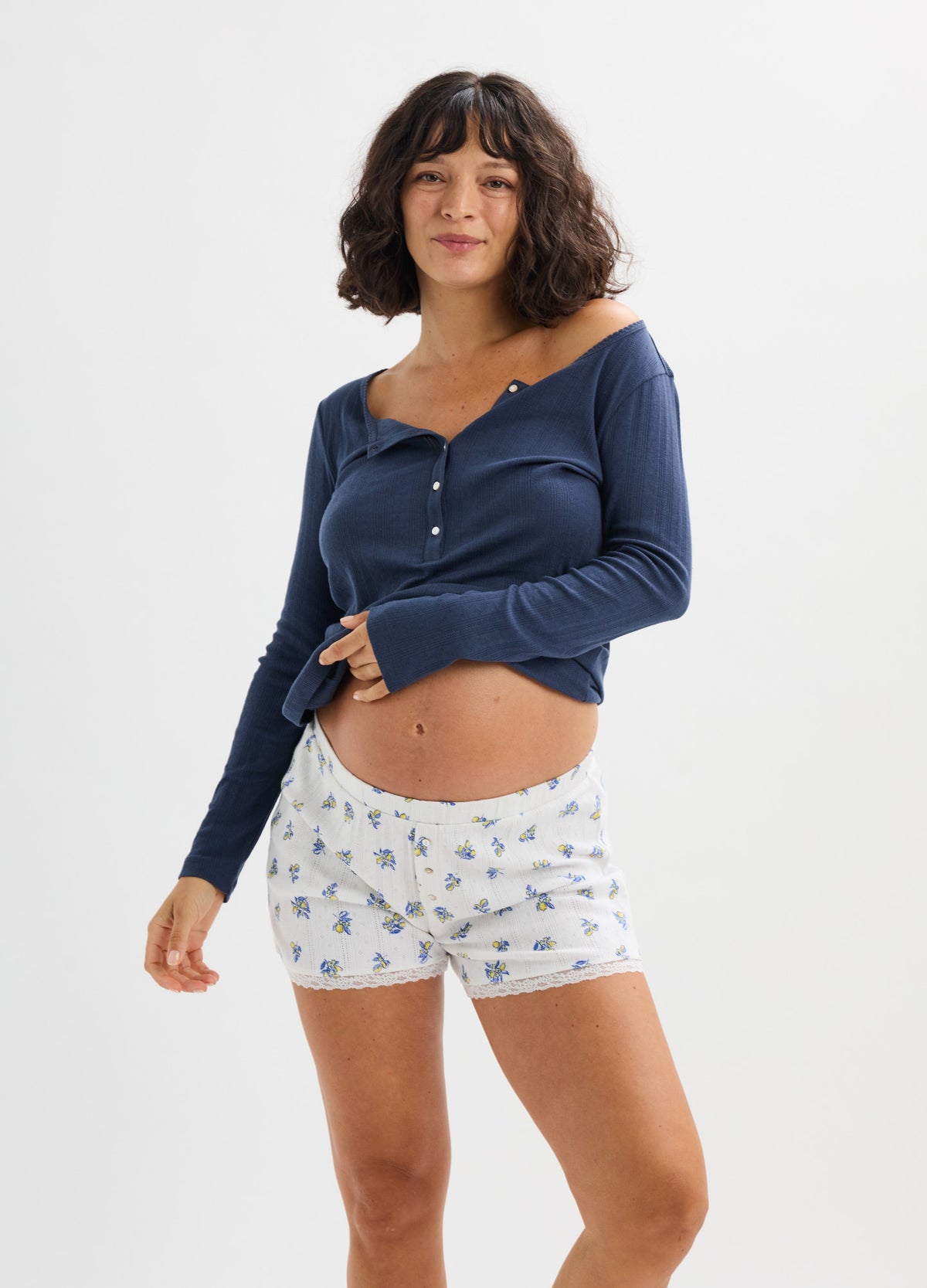 Navy long sleeve ribbed henley top with button details, worn with white floral maternity shorts.