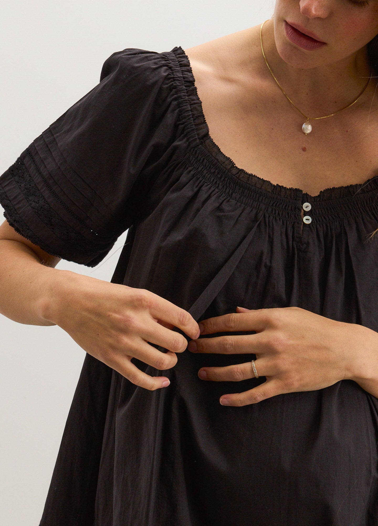 Black maternity nursing mini dress with puff sleeves and button detail at the front neckline.