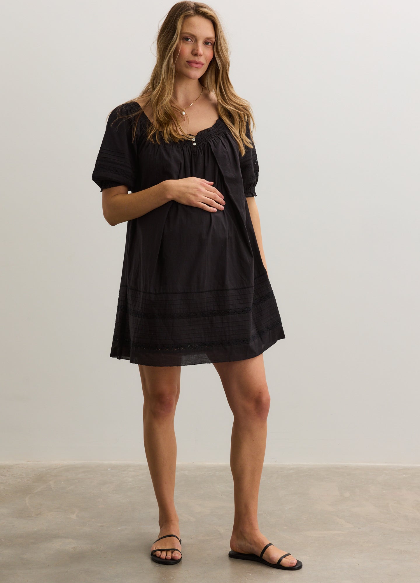 Black short-sleeve maternity mini dress with square neckline and gathered bodice detailing.