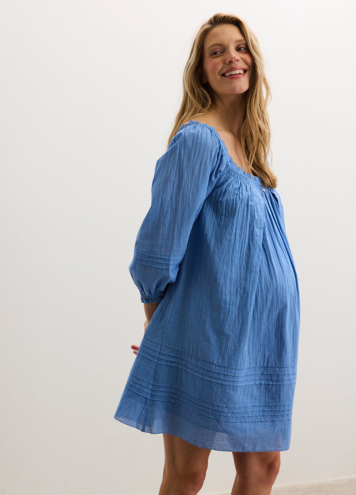 Light blue maternity mini dress with puff sleeves and smocked square neckline.