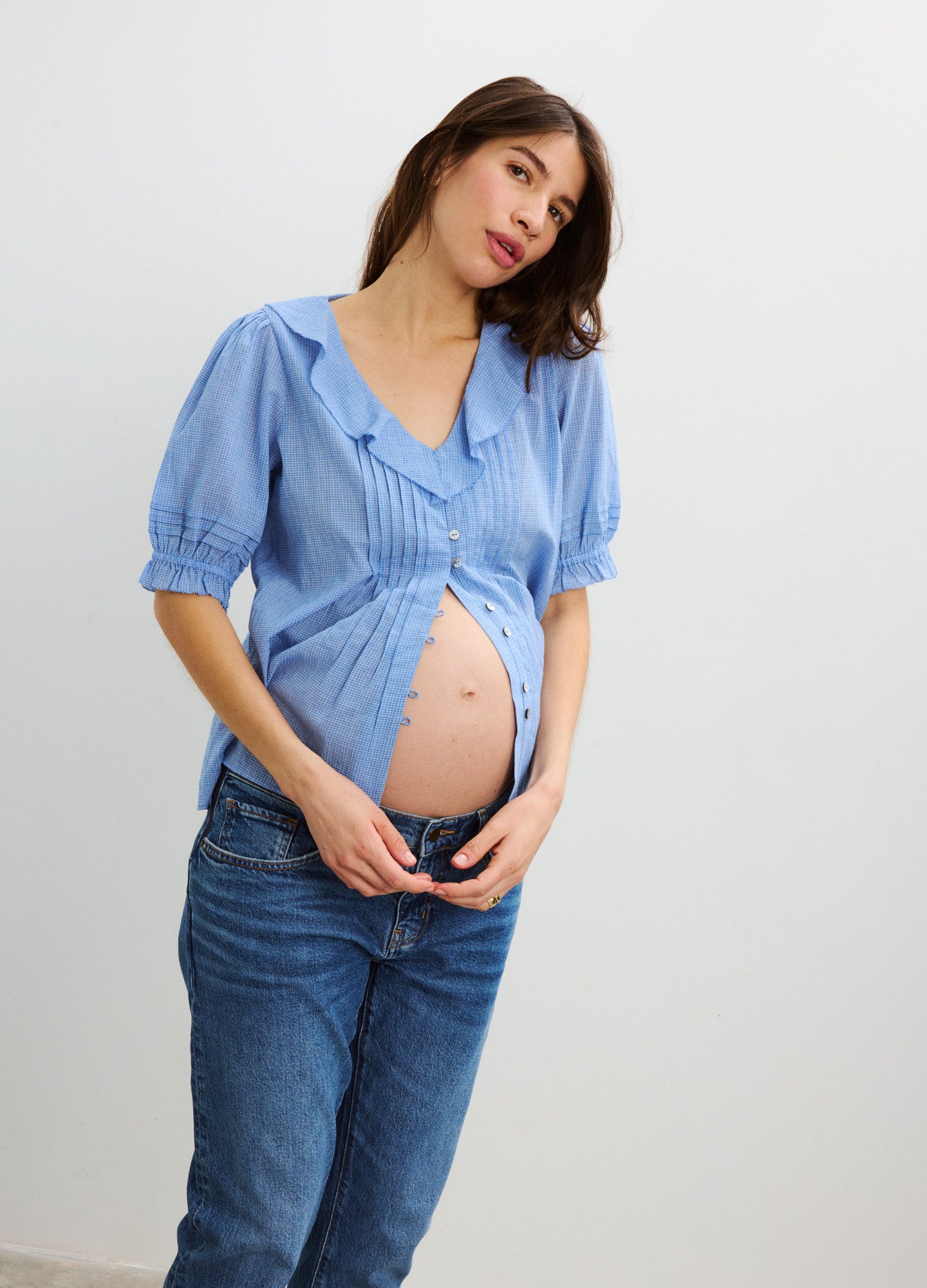 Light blue plaid nursing blouse with puff sleeves and front buttons, worn open over maternity jeans.